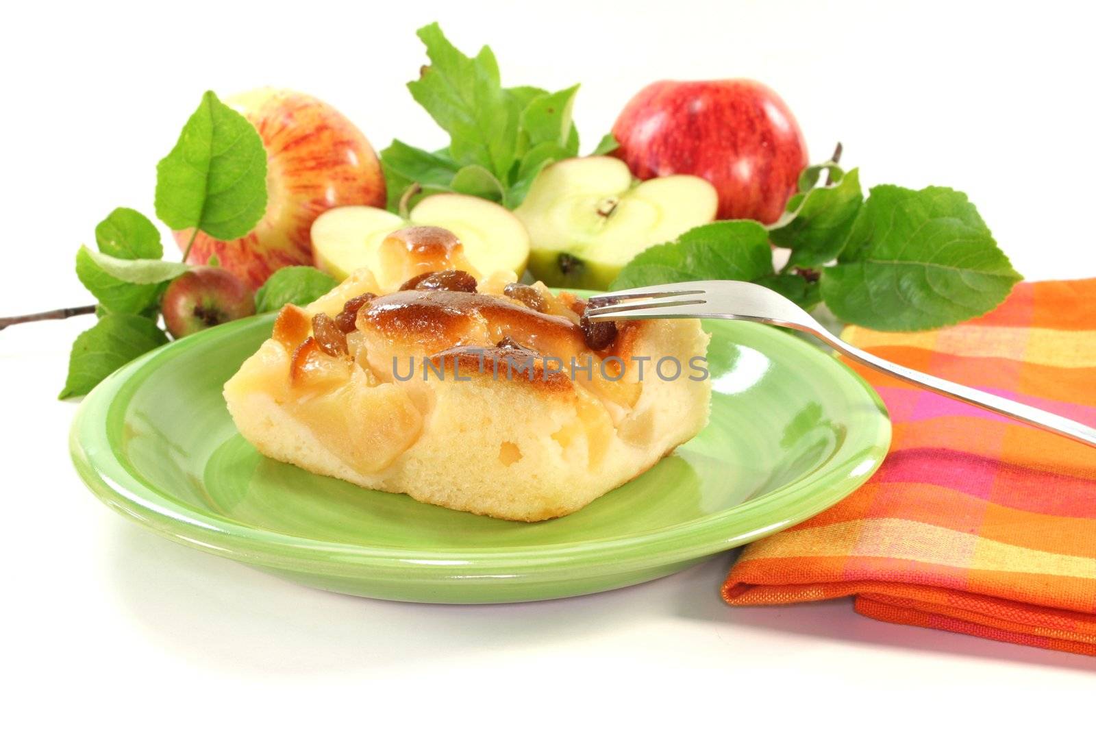 a piece of apple cake with apples and leaves on a white background