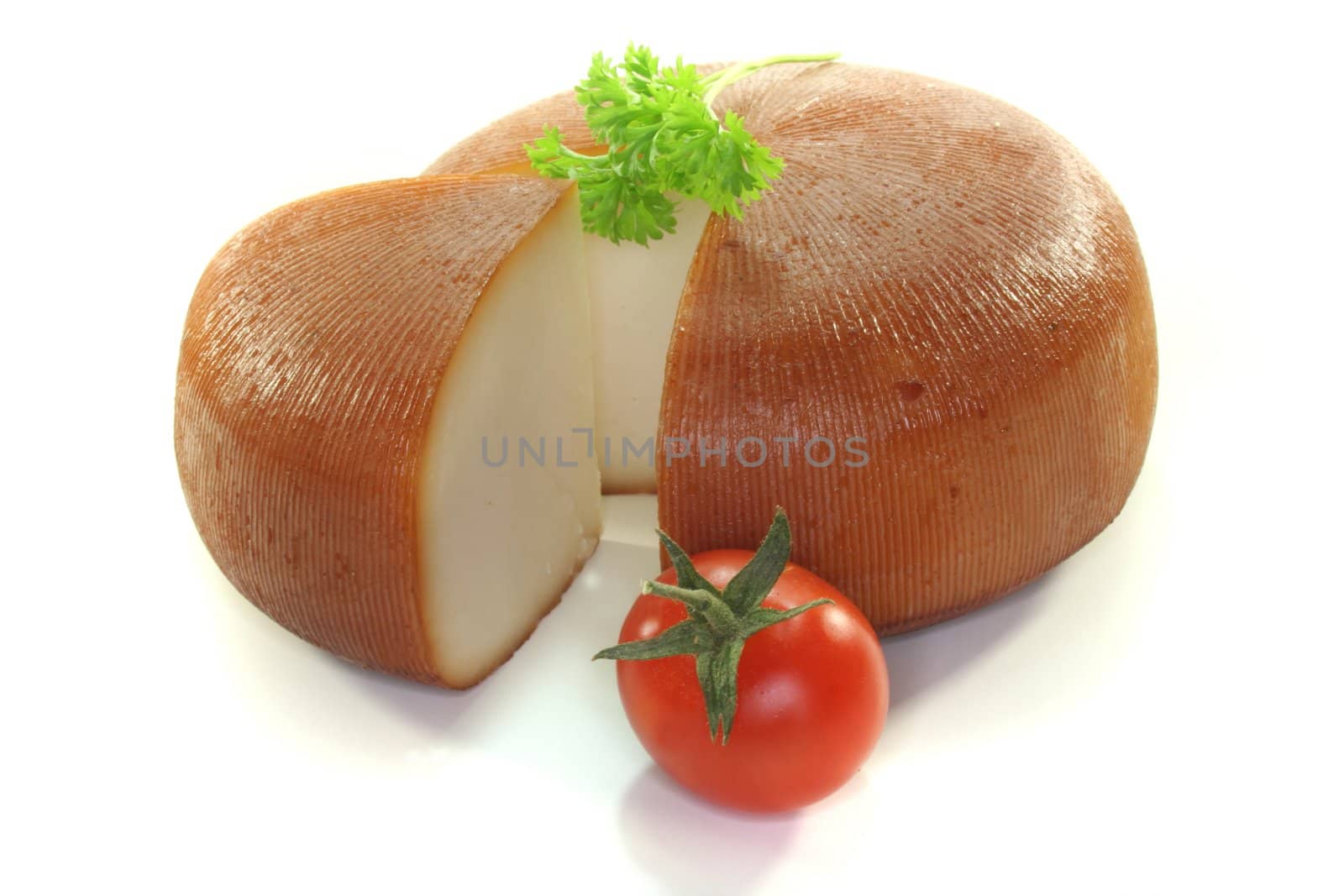 a loaf of smoked goat cheese with parsley and tomato on a white background