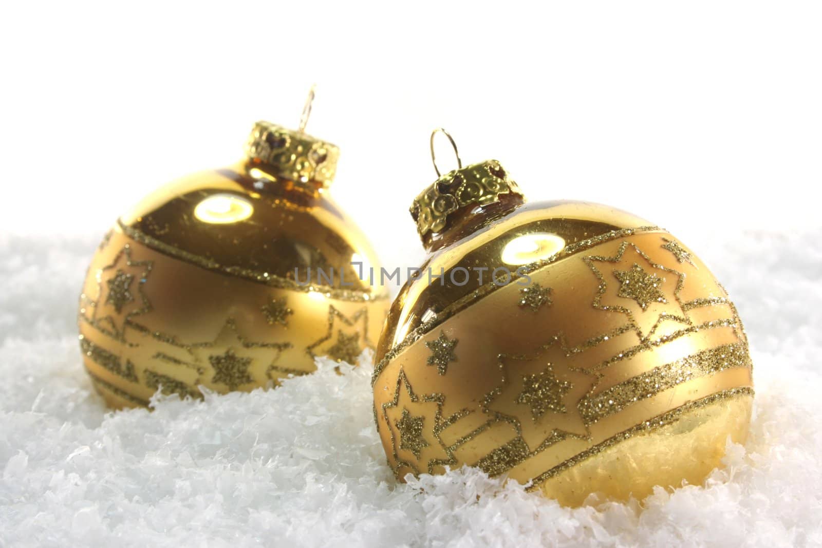 two golden Christmas balls lying in the snow