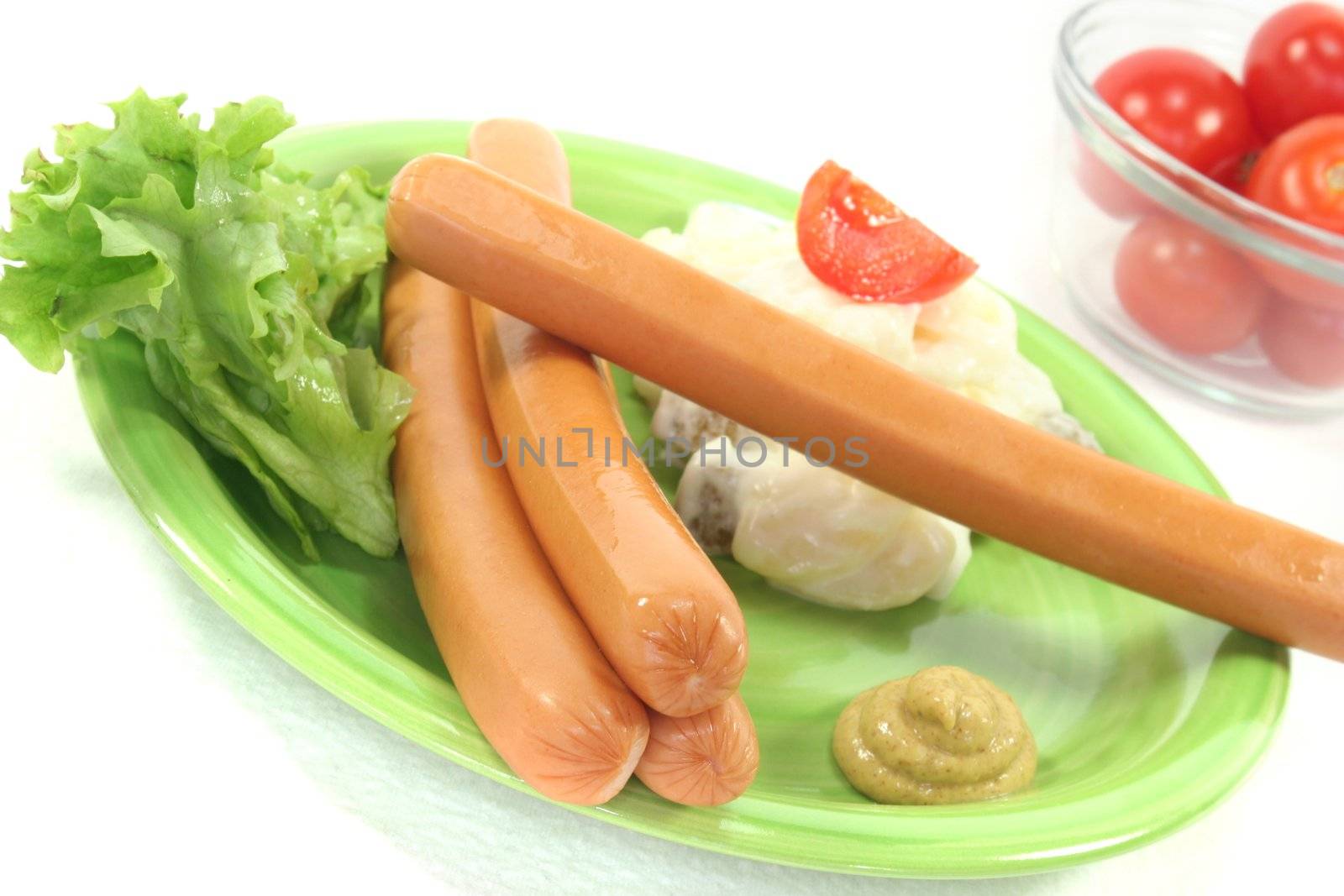 Wiener Sausage with potato salad and lettuce on a white background