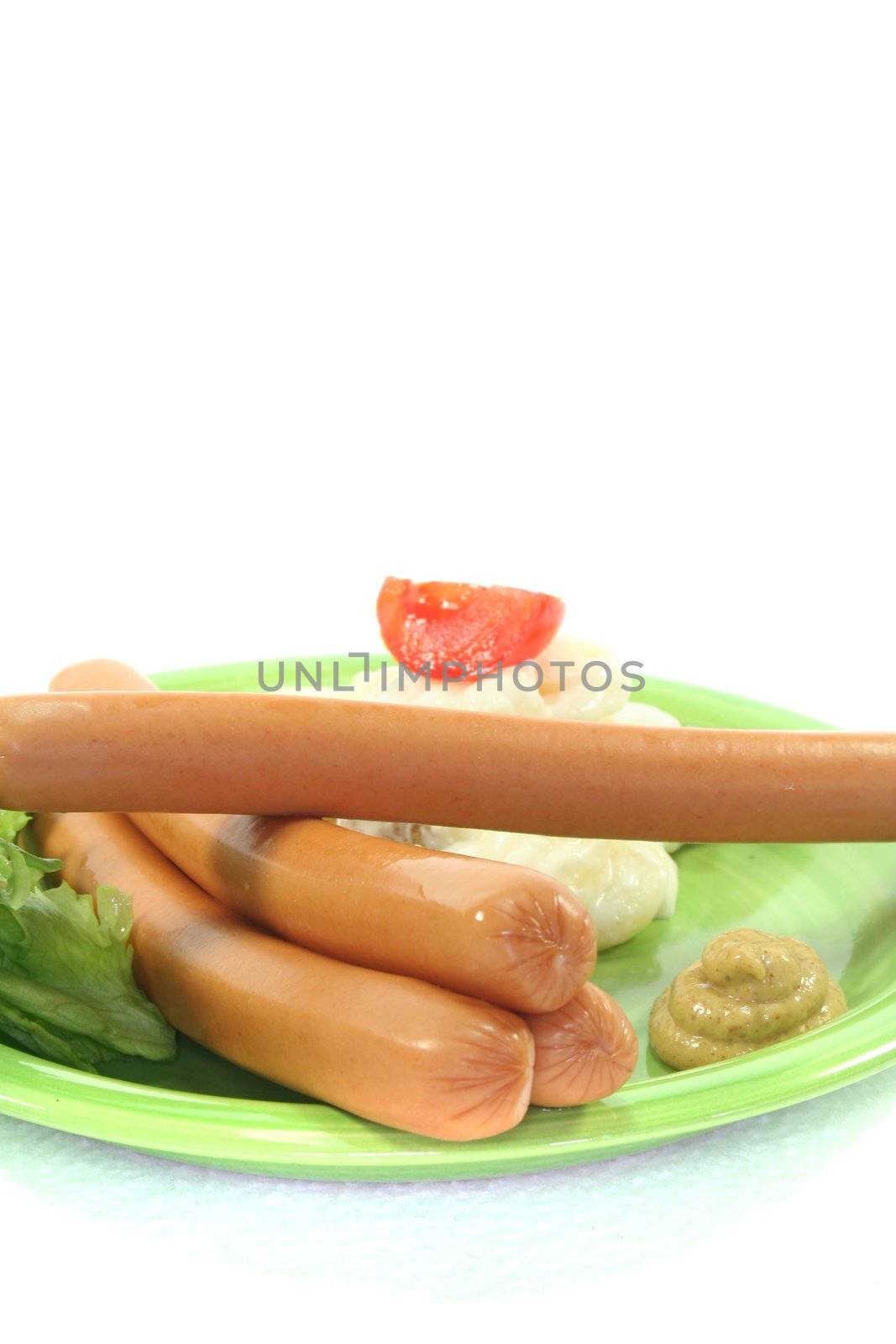 Wiener Sausage with potato salad and lettuce on a white background