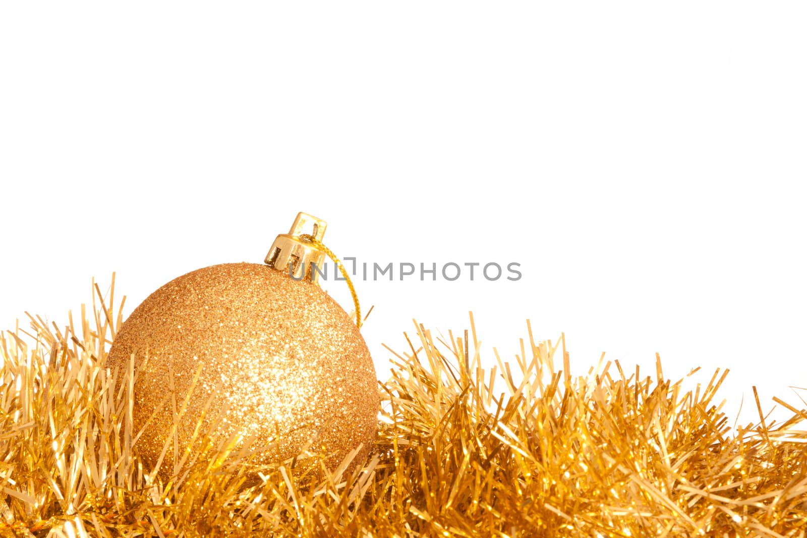 A glittering golden Christmas bauble on some tinsel isolated on white.