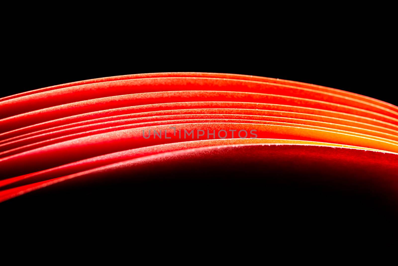 red A4 paper illuminated with lights with black background forming a fiery red curve
