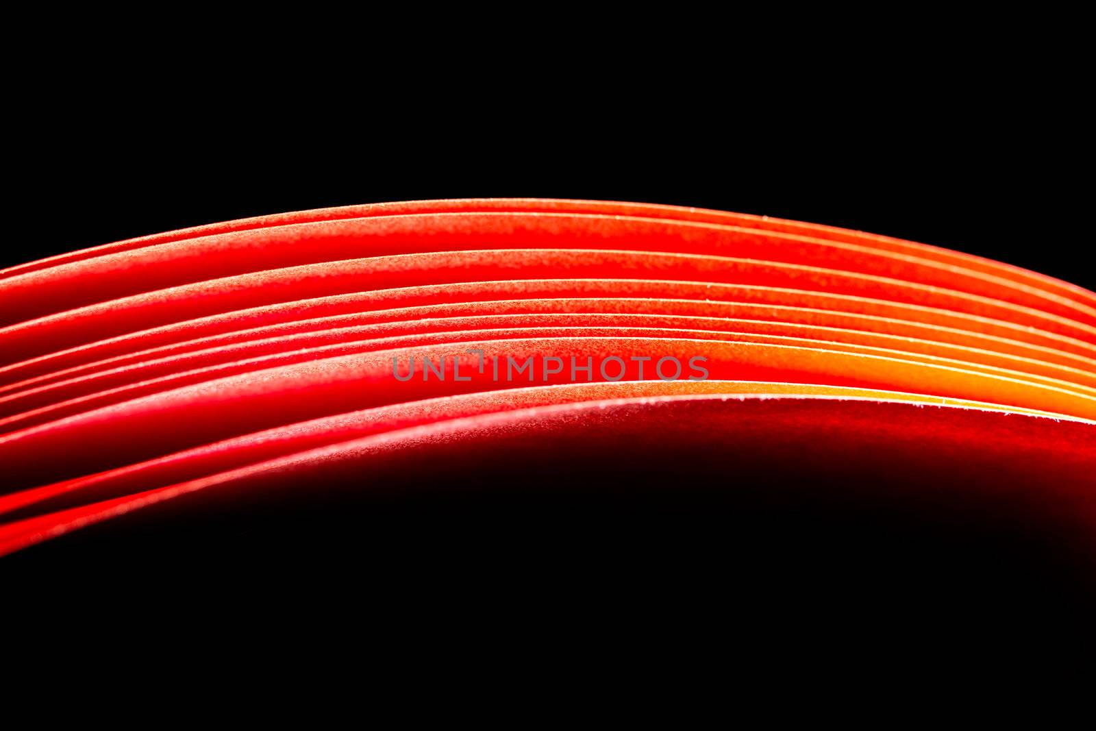 red A4 paper illuminated with lights with black background forming a fiery red curve