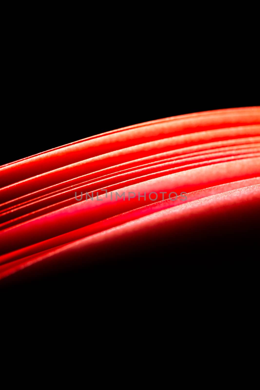 red A4 paper illuminated with lights with black background forming a fiery red curve