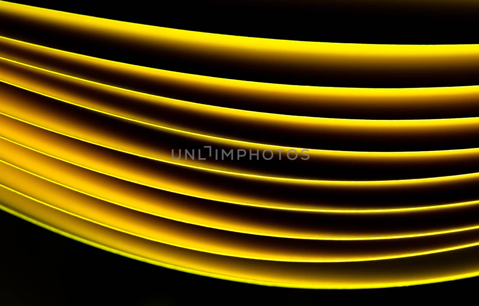 Yellow A4 paper illuminated with LED lights on black background