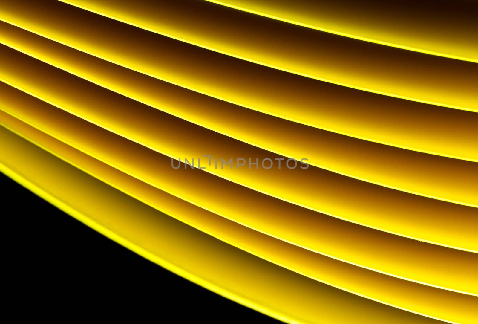 Yellow A4 paper illuminated with LED lights on black background