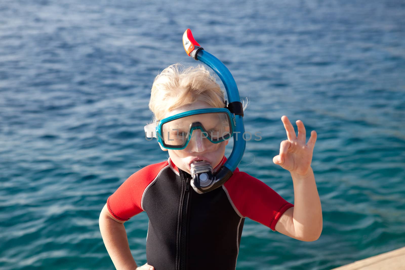 child in a diving mask showing ok