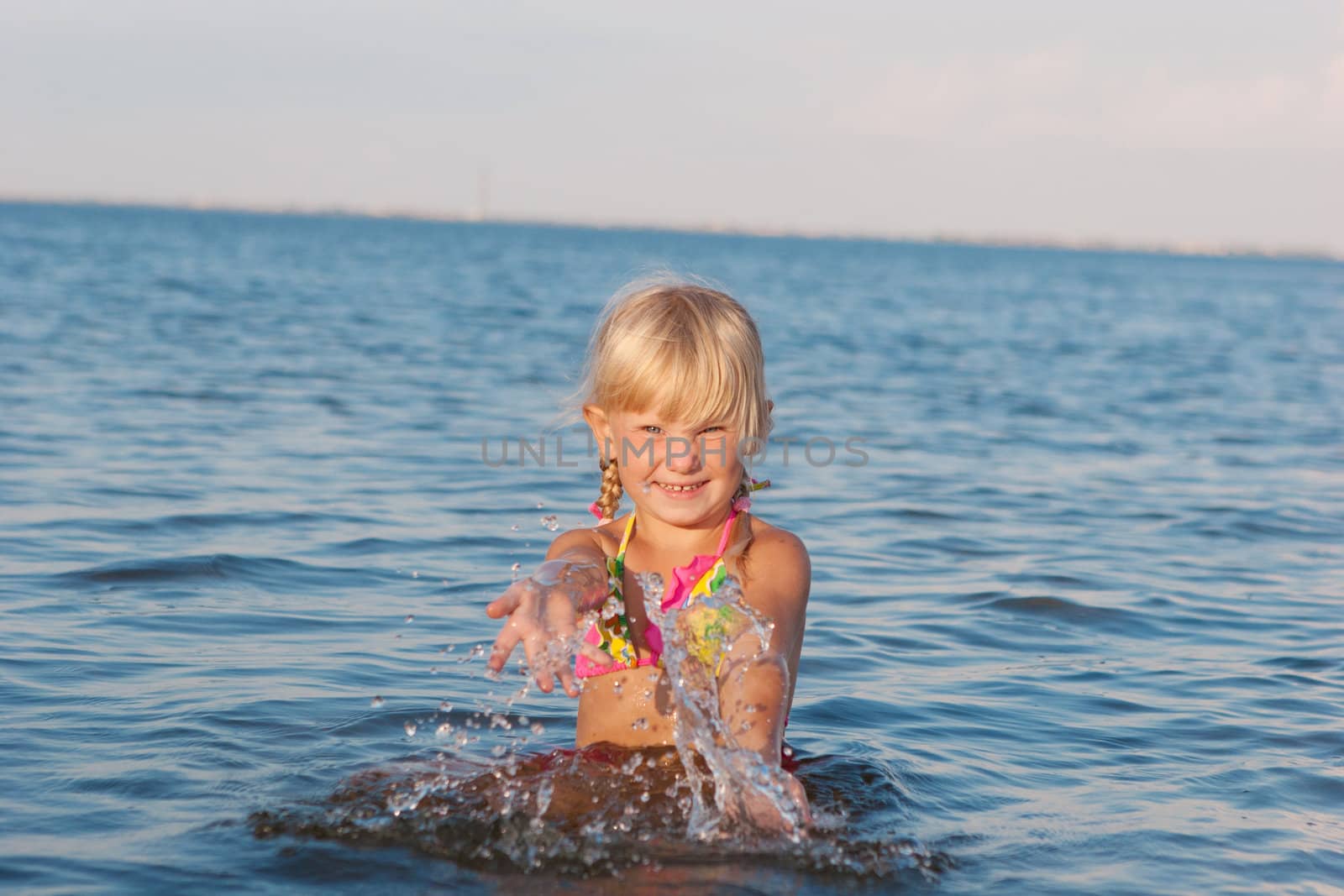 happy girl splashing in water at the evening