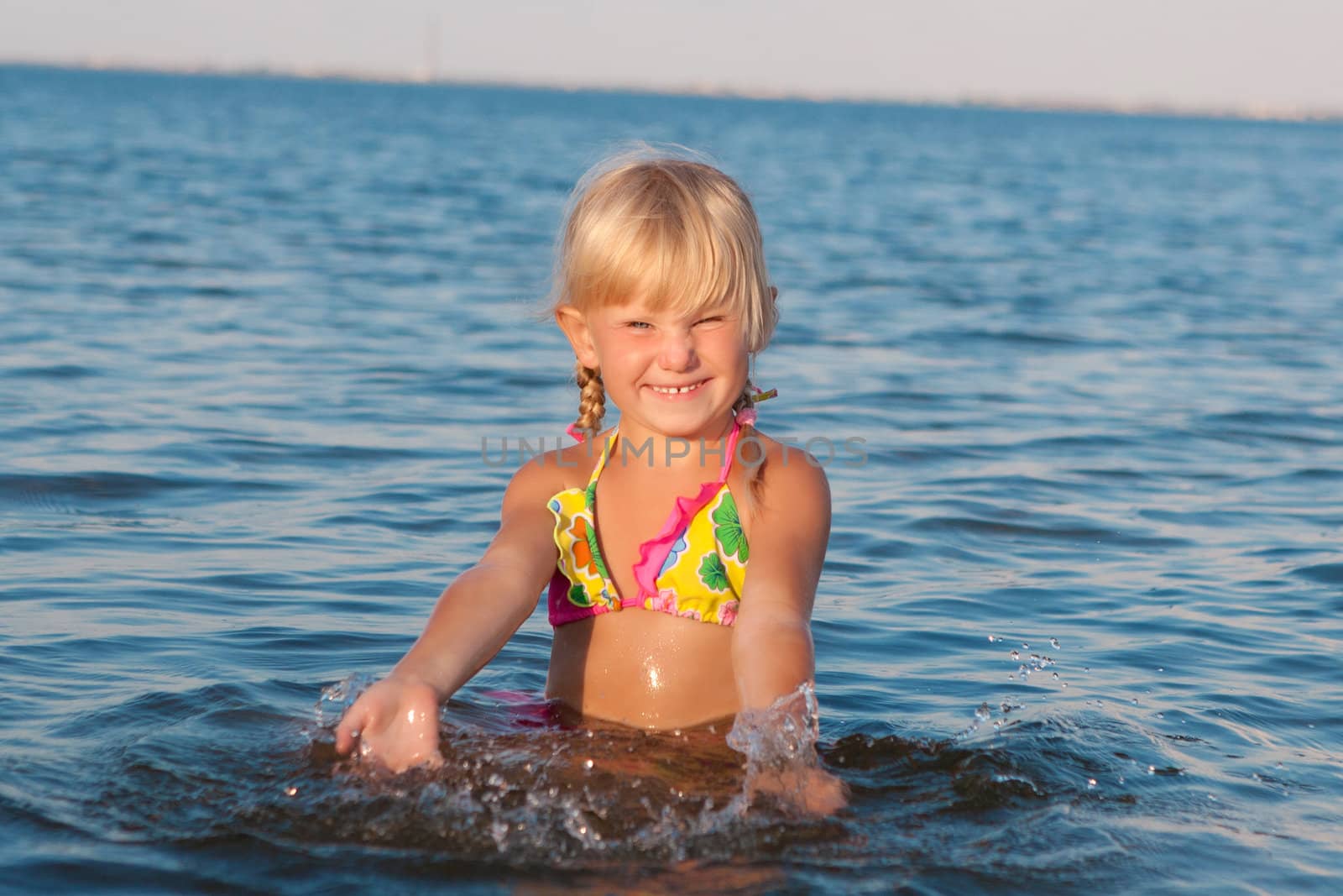 happy girl splashing in water at the evening