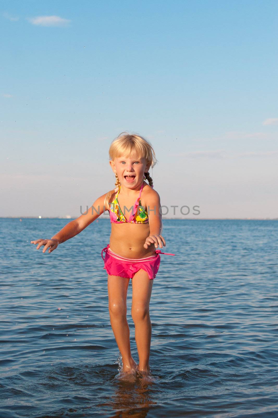 happy girl jumping in water at the evening