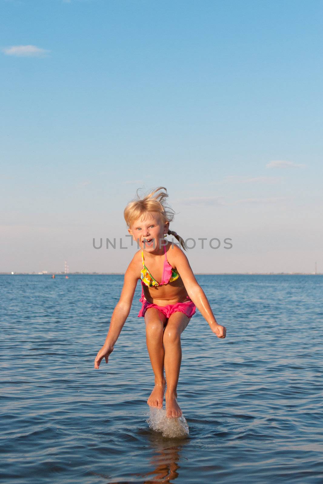 happy girl jumping in water at the evening