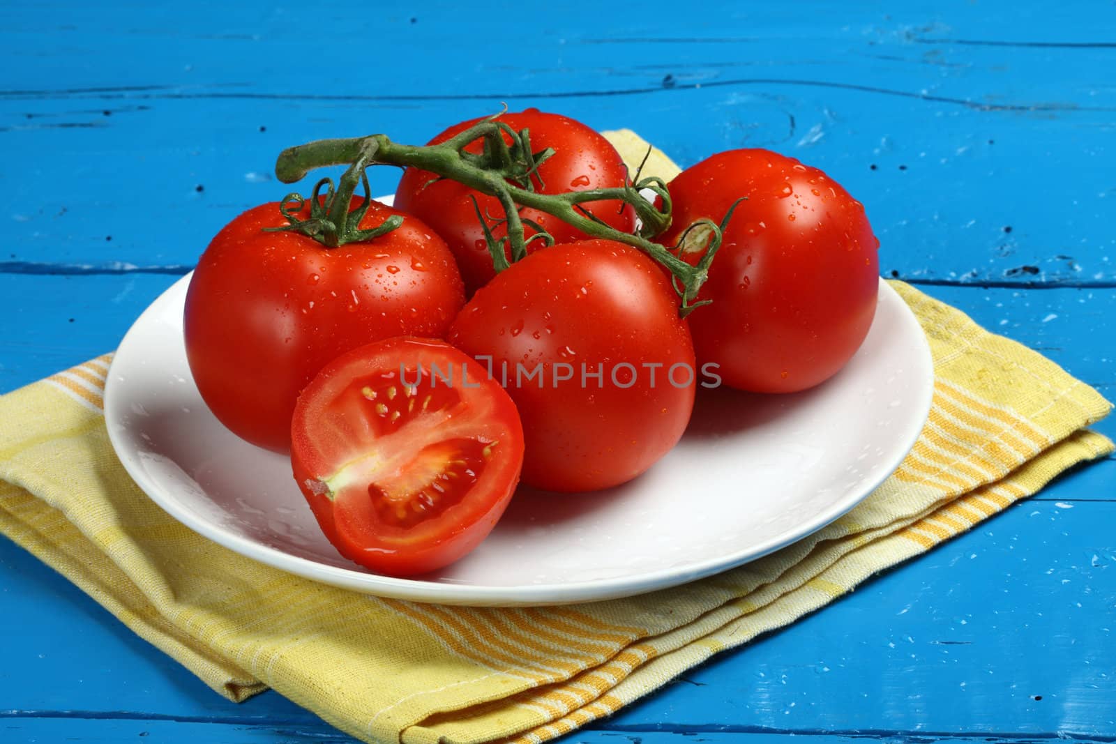 Close up of fresh tomatoes in plate on blue table