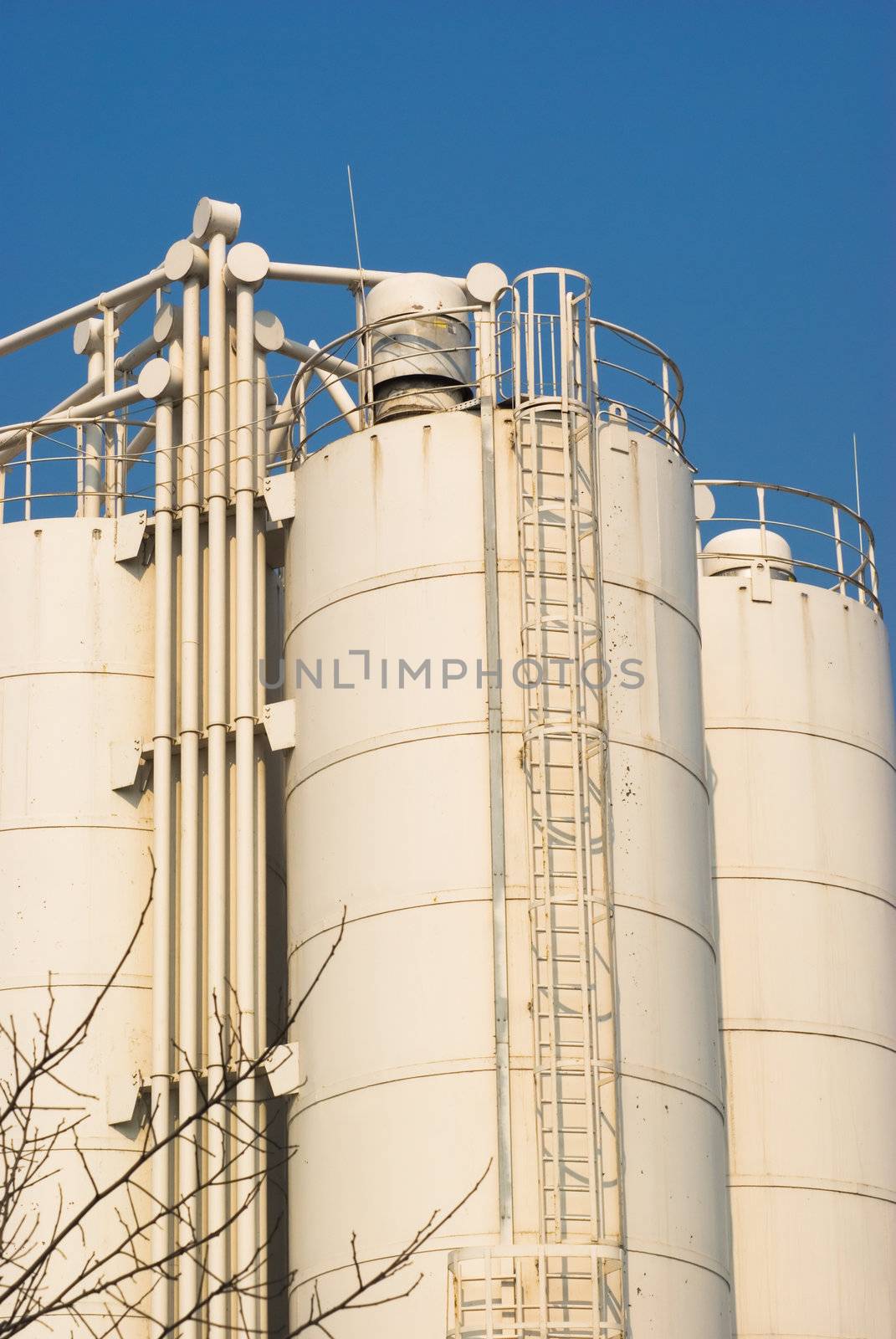 Low-angle shot of ladder and tanks refinery