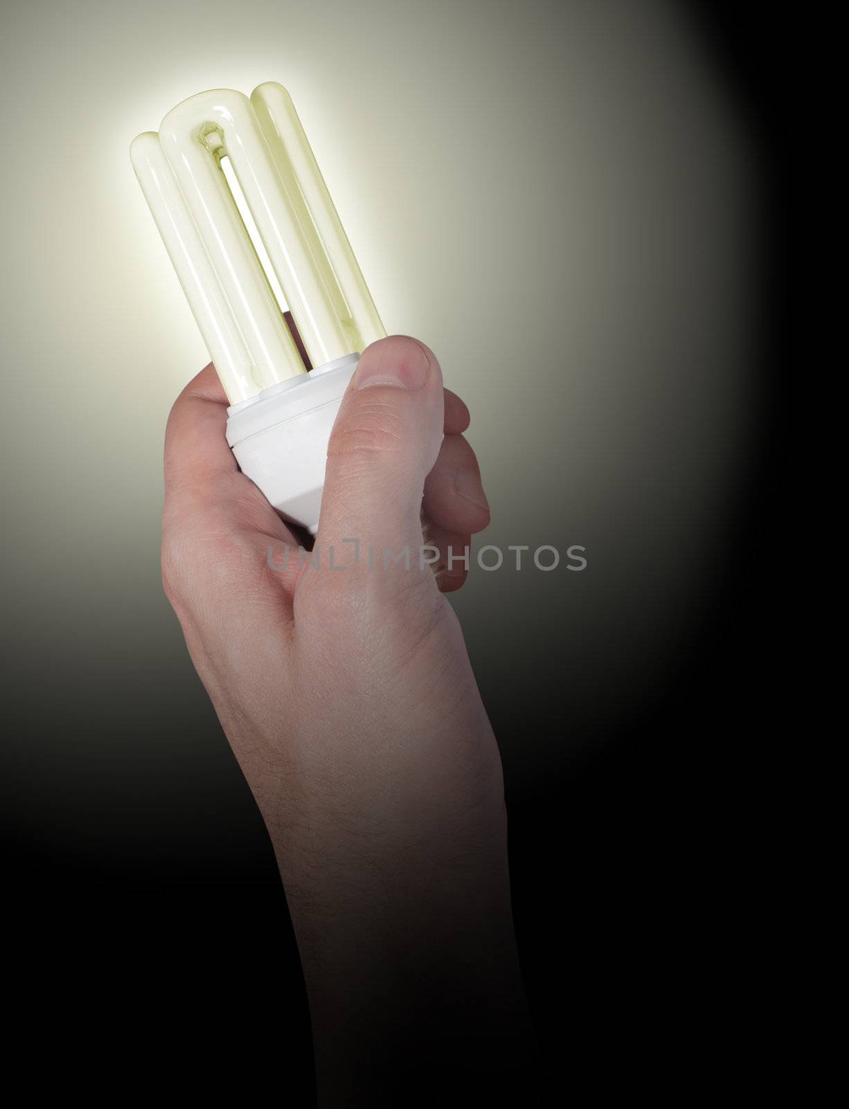 Glowing Energy Saving Bulb in Hand on Black Background