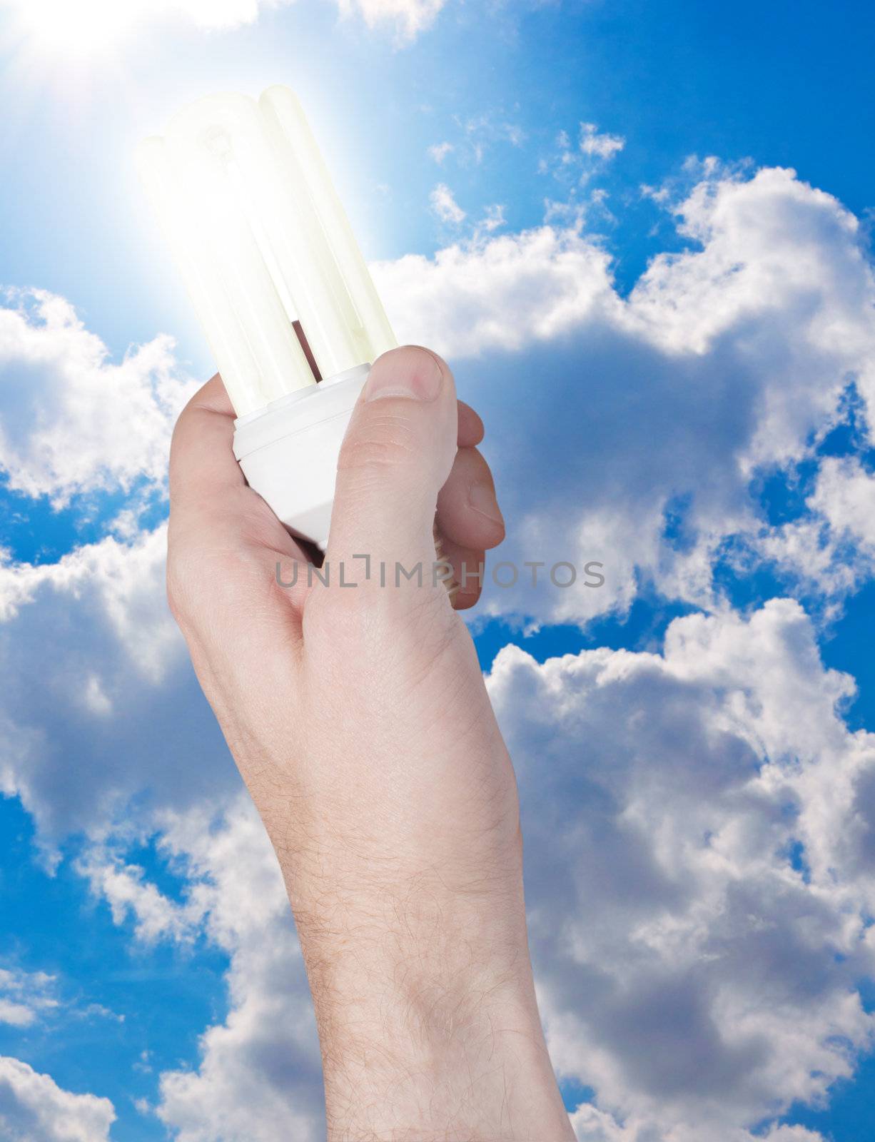 Glowing Energy Saving Bulb in Hand on Blue Sky Background