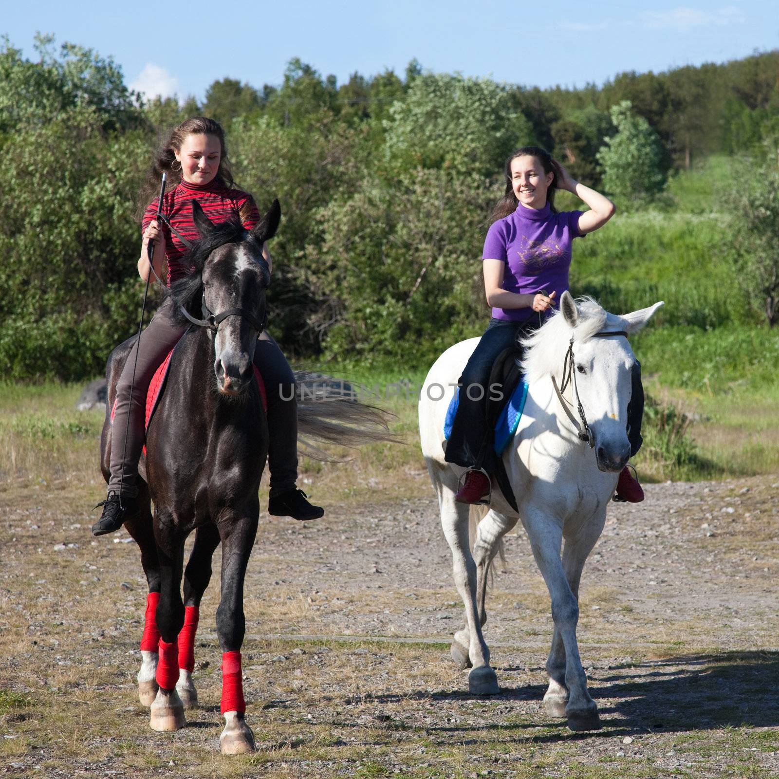 Two girls on horseback, on a clear sunny day