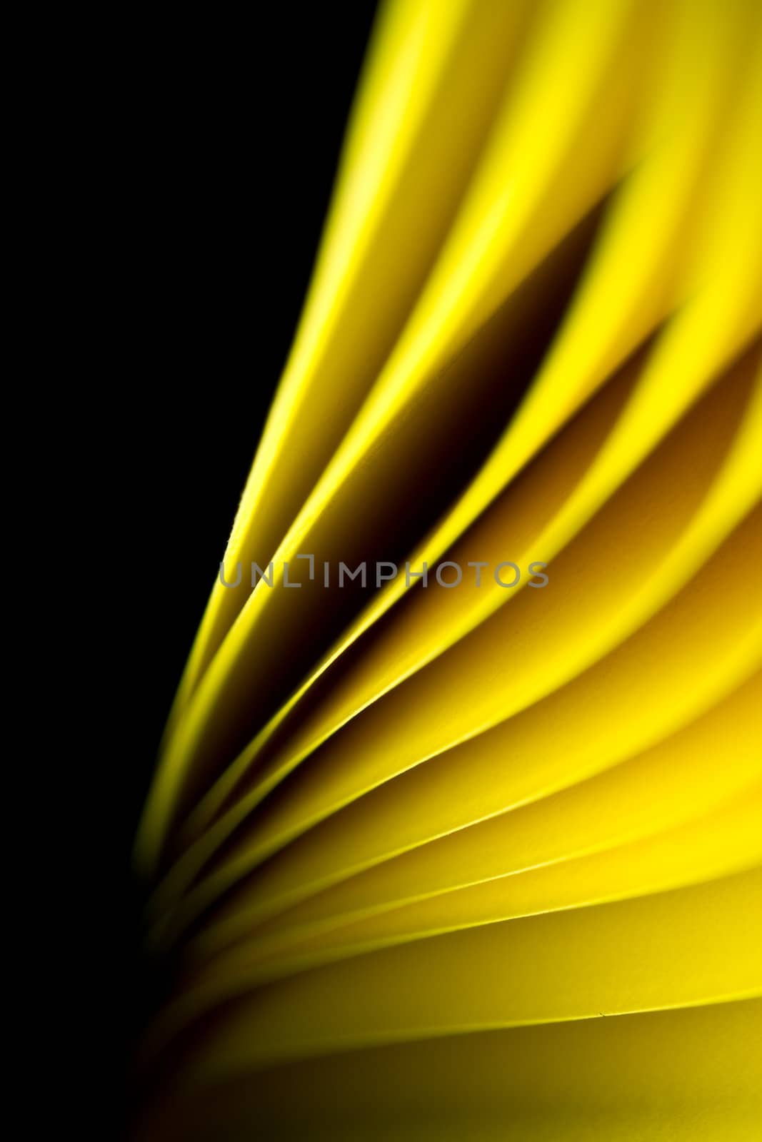 Yellow A4 paper illuminated by LED lights and twisted with black background