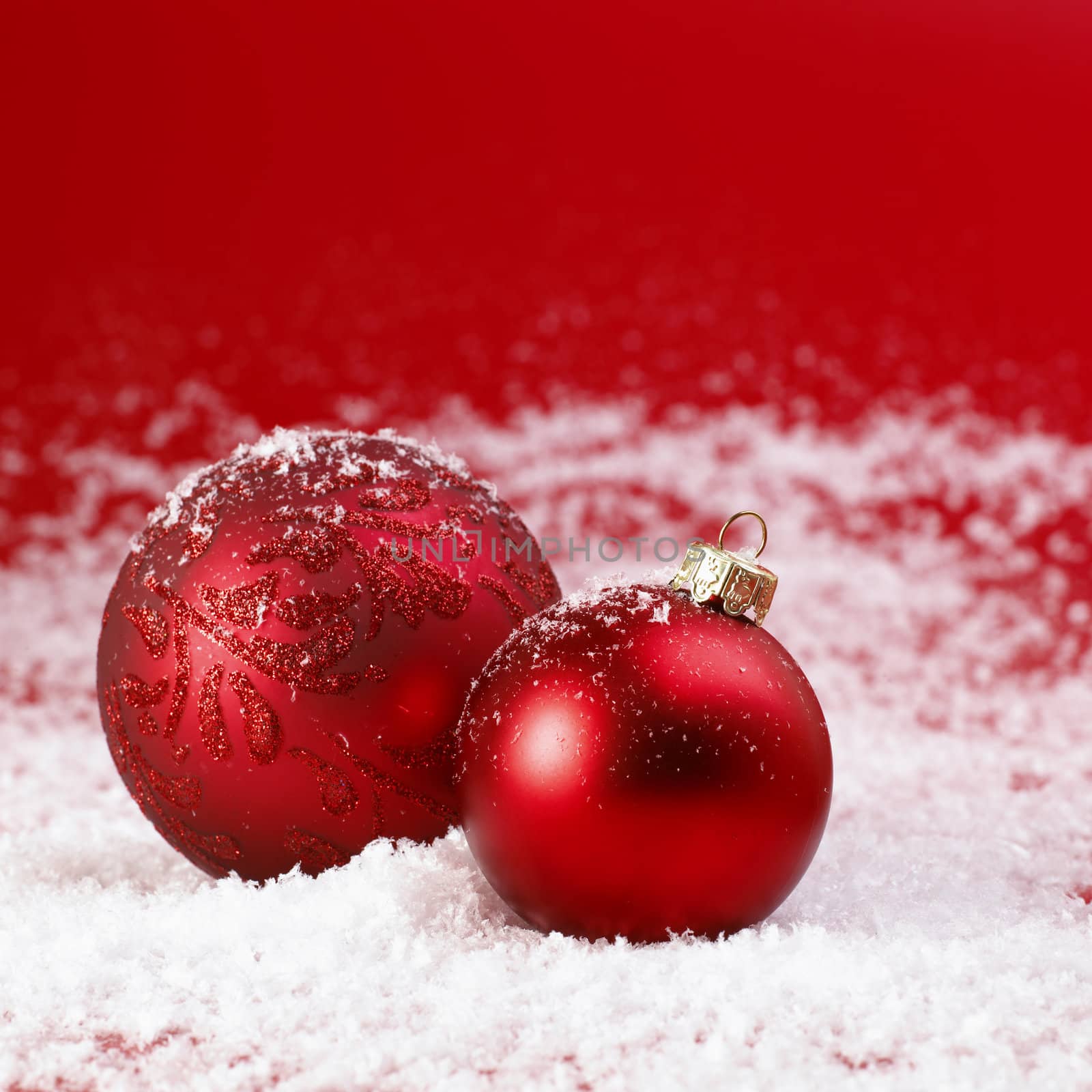 Red Christmas baubles on snow.