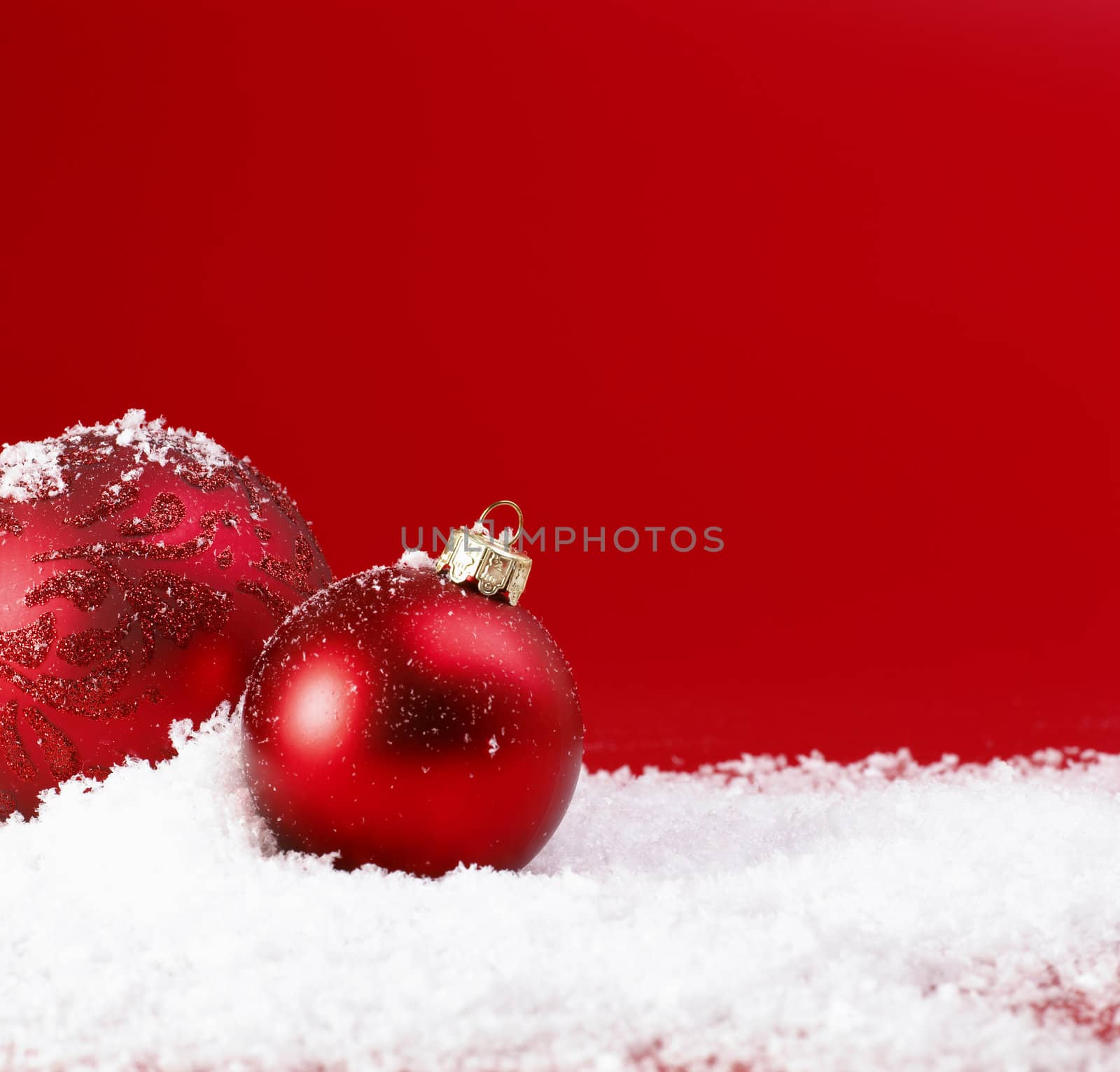 Red Christmas baubles on snow.