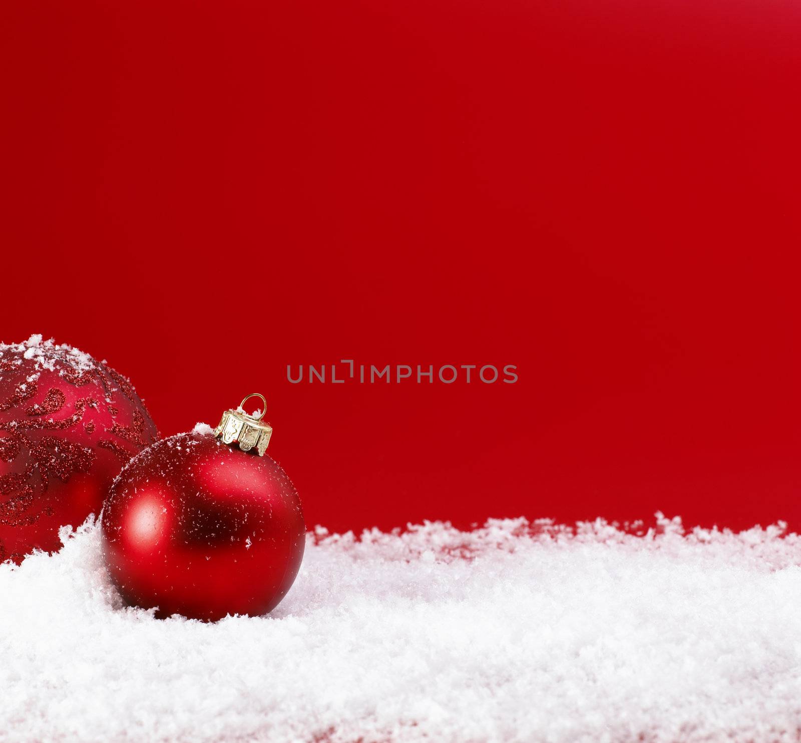 Red Christmas baubles on snow.