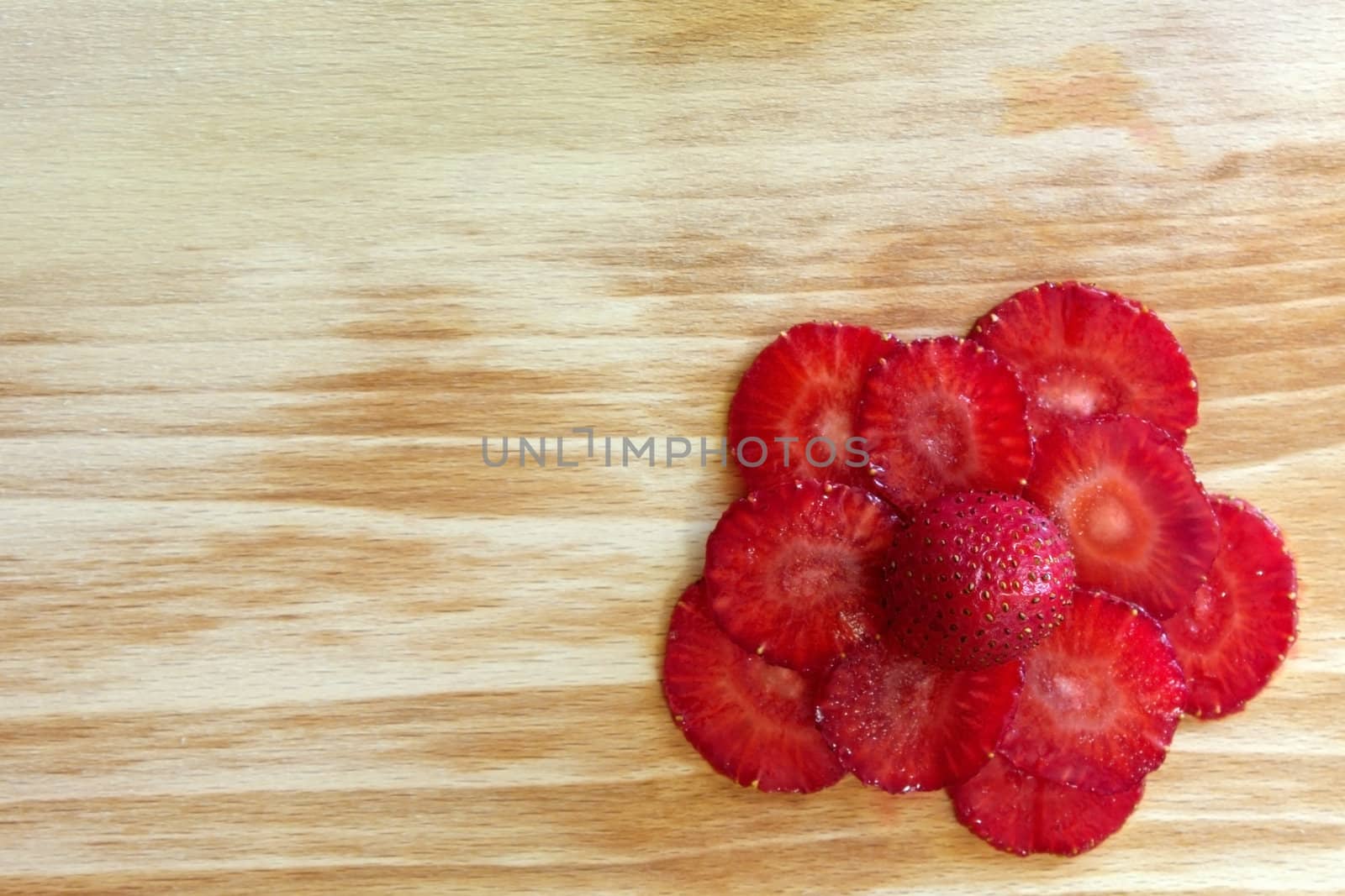 strawberries slices composed as flower on the cutting board in the right bottom corner