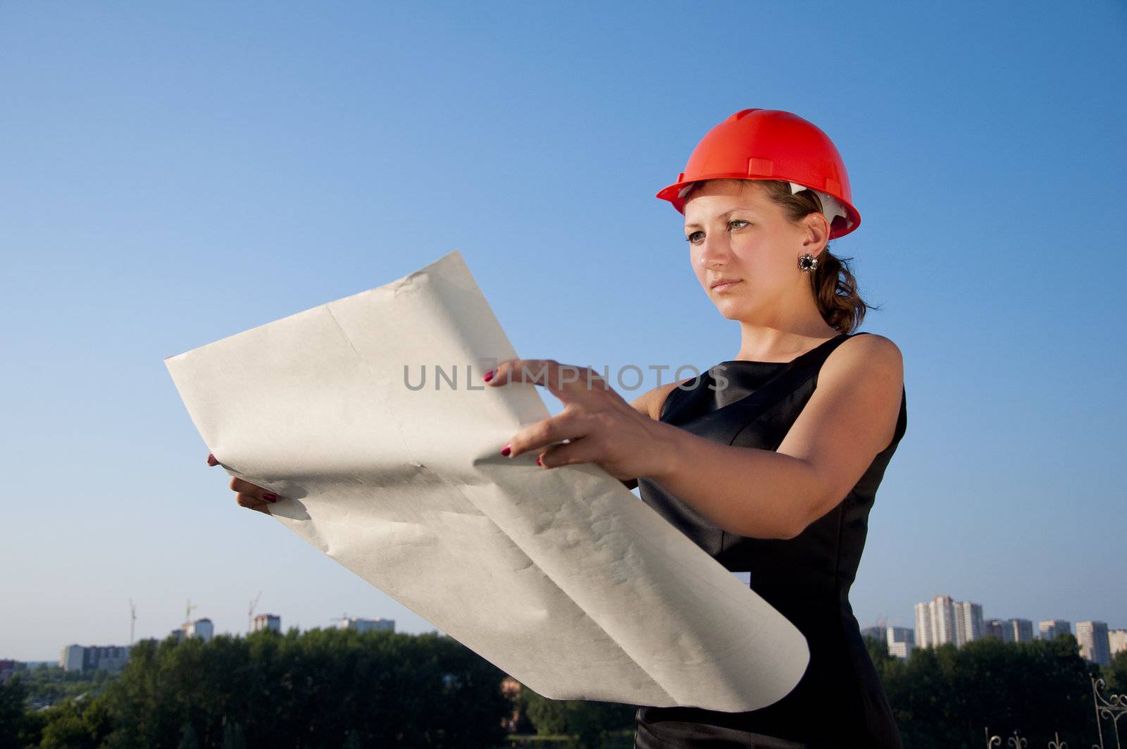 Business woman considers construction plans, blue sky background