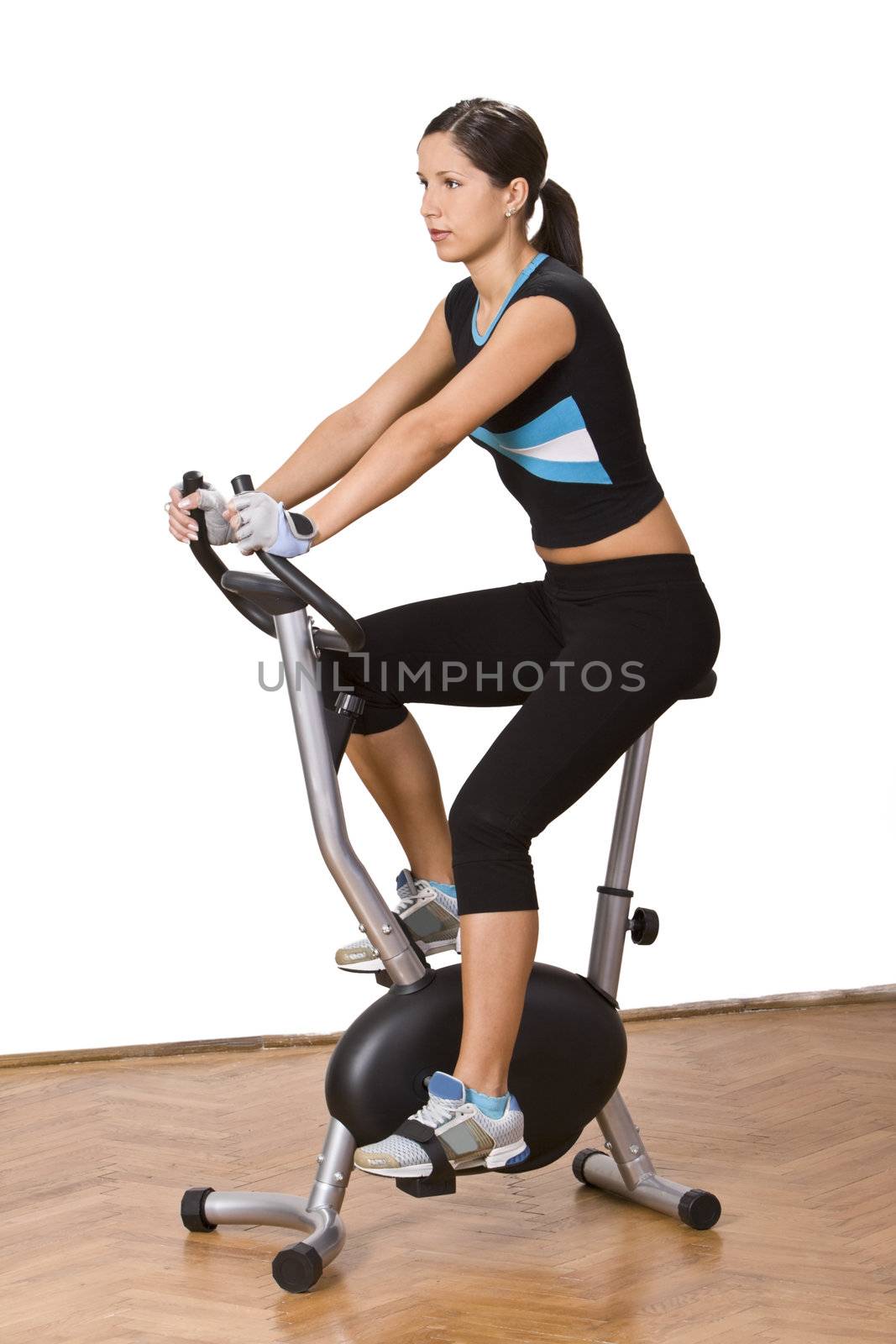 Girl riding a fitness bicycle in a gym.