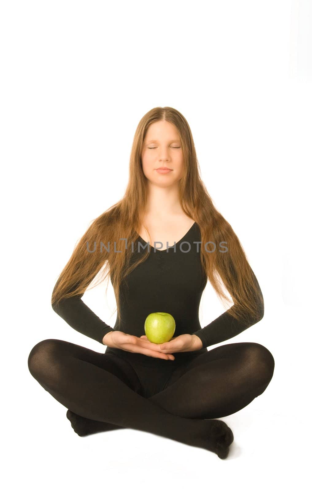 The portrait of a woman in lotus pose with a green apple in her hands
