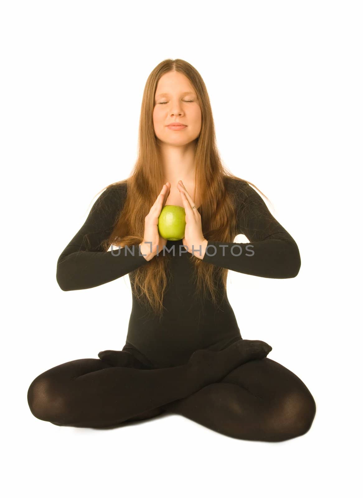 The portrait of a woman in lotus pose with a green apple in her hands