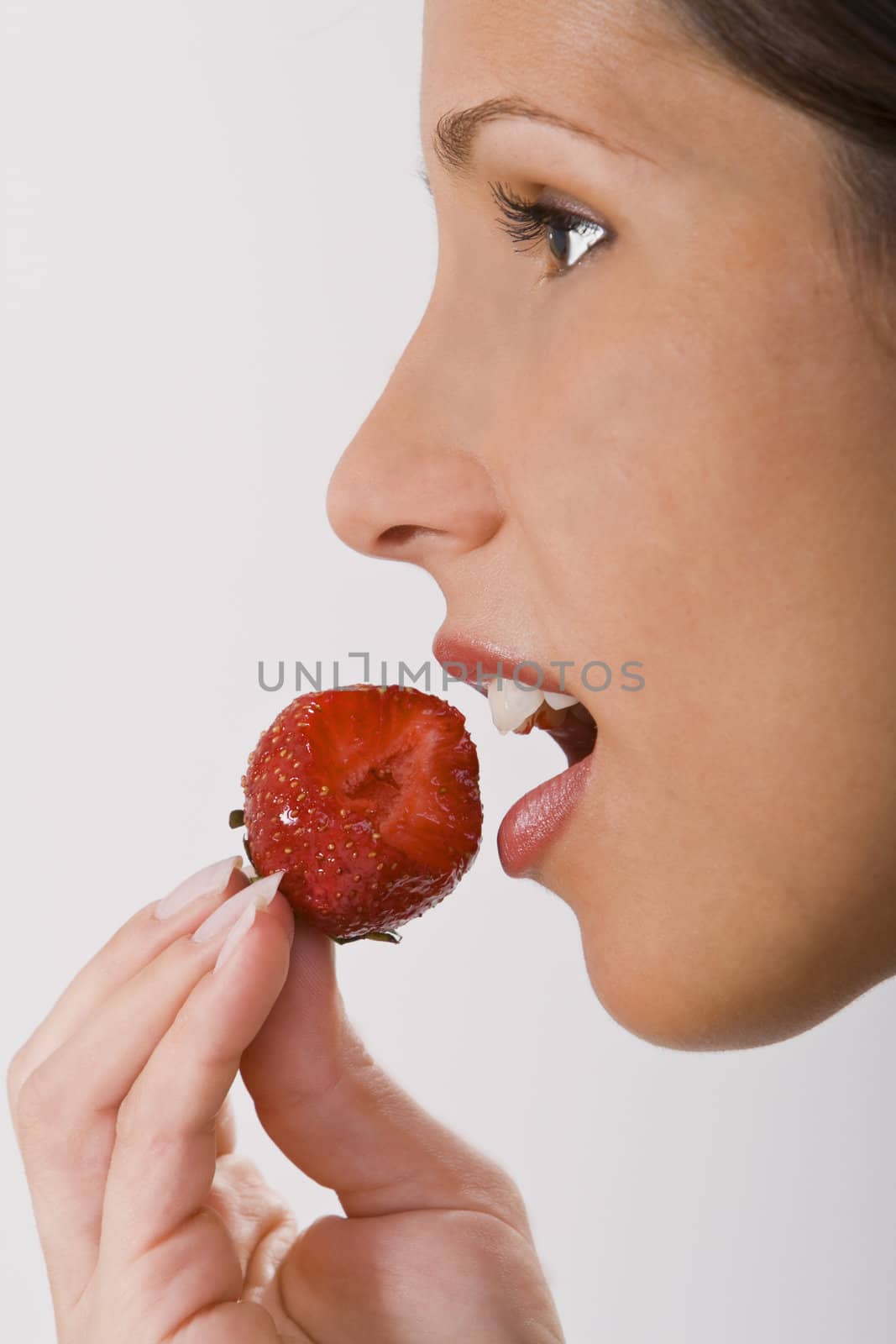 Close-up of a woman mouth bitting into a strawberry.