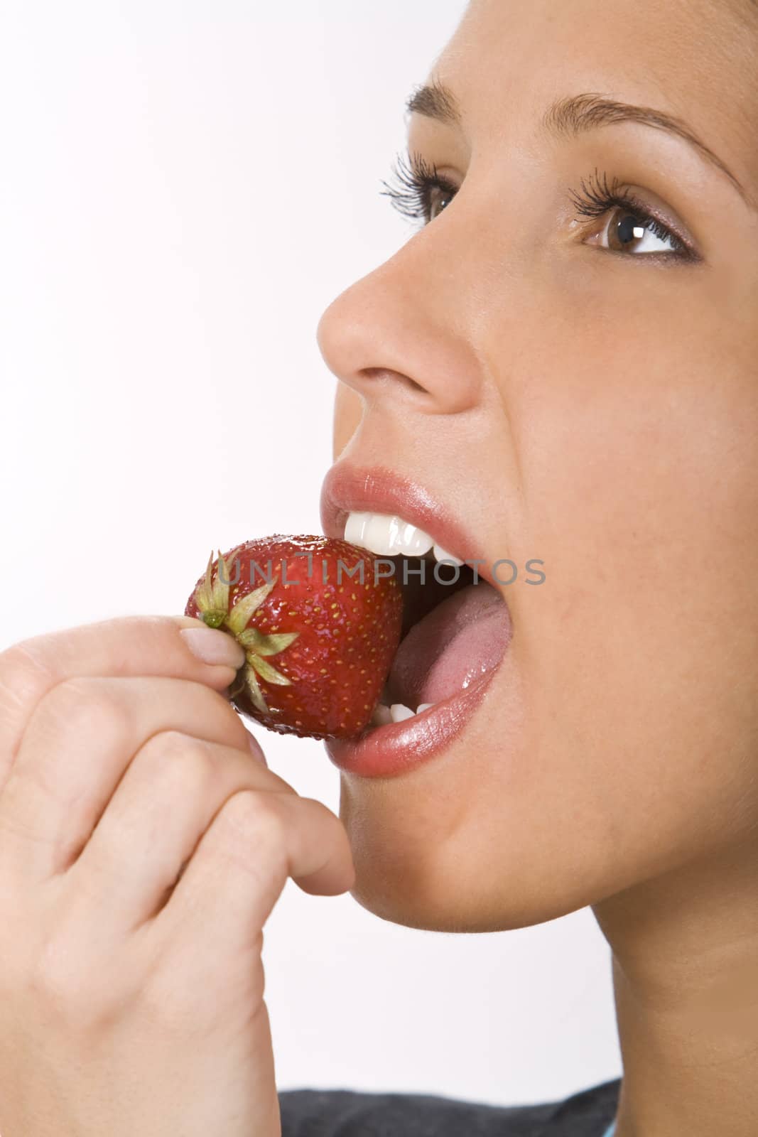 Close-up of a woman mouth bitting into a strawberry.