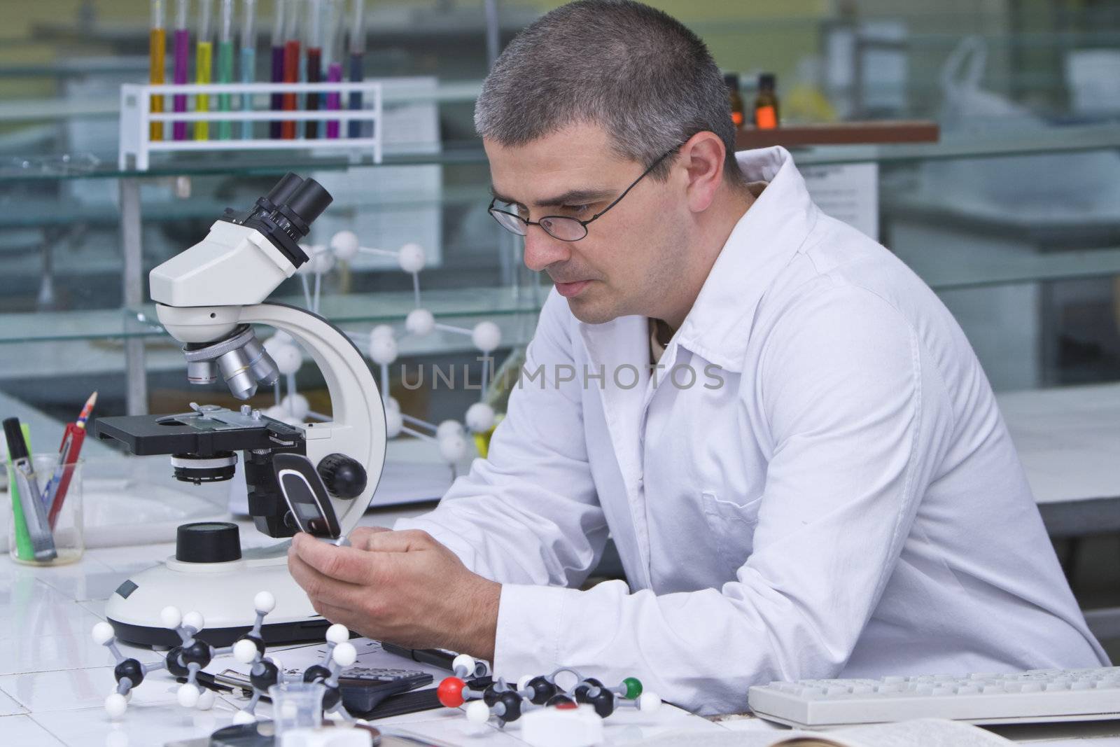 A male researcher checking the mobile phone at his workplace in a laboratory.