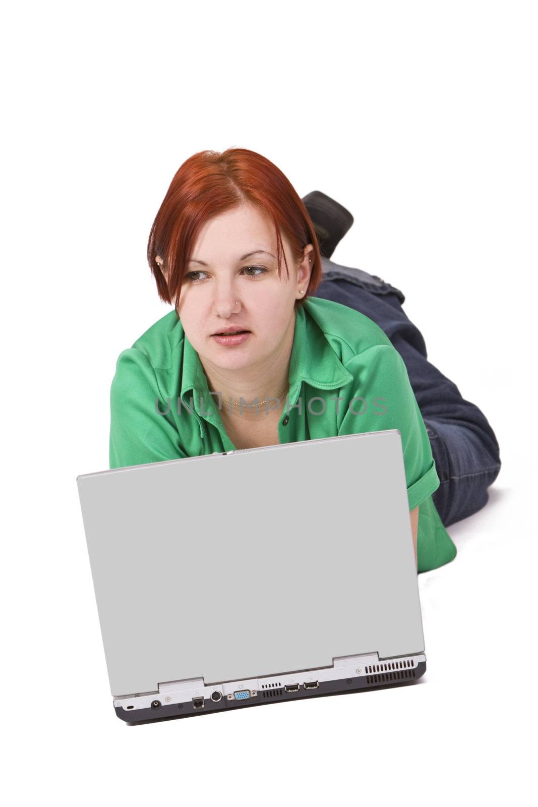 Portrait of a smilling redheaded teenage girl lying down in front of a laptop.