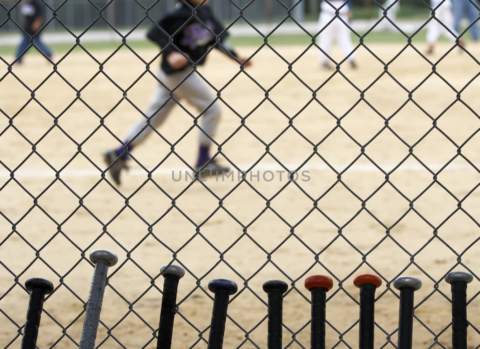 baseball bats learning against dugout fence as game is played