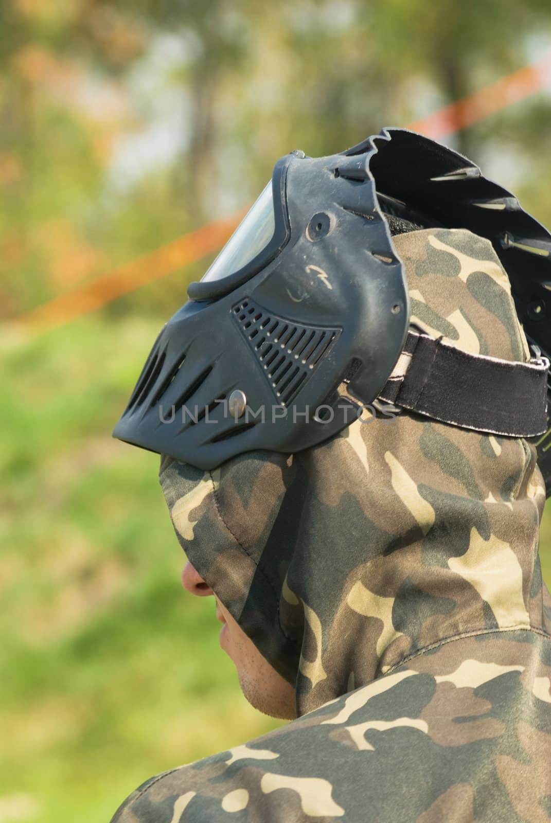 A teen in camouflage and mask ready for paintball.