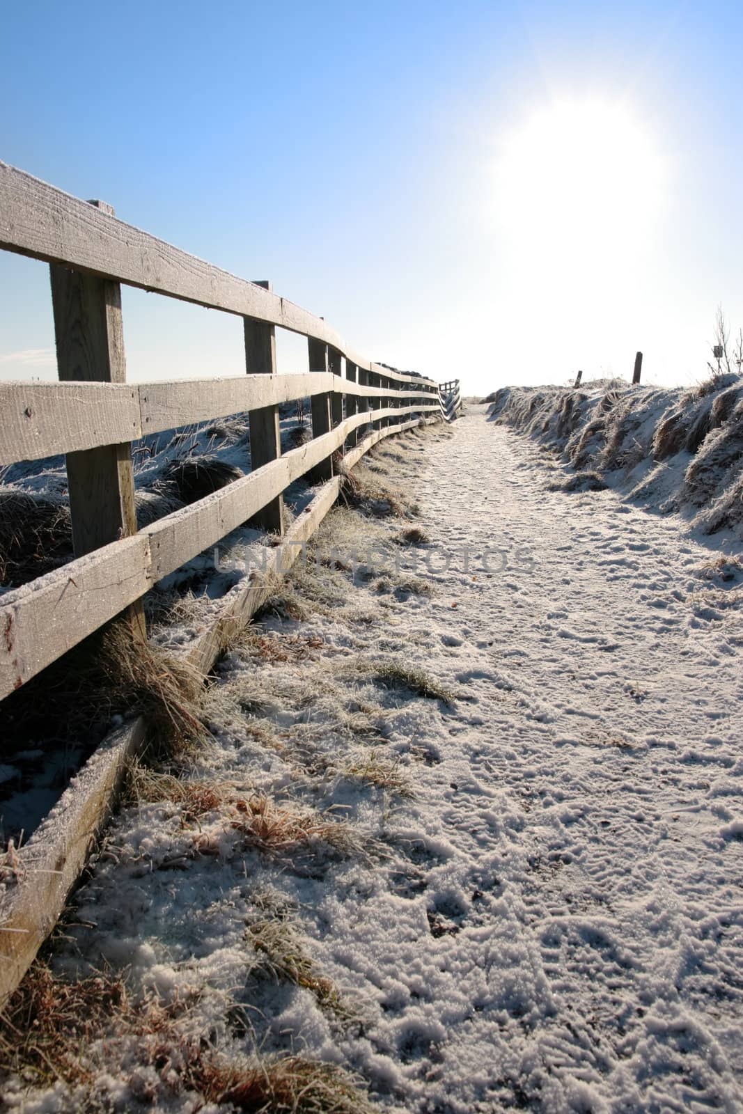 frosty blue winters view at ballybunion cliffside walk with bright sun and fence
