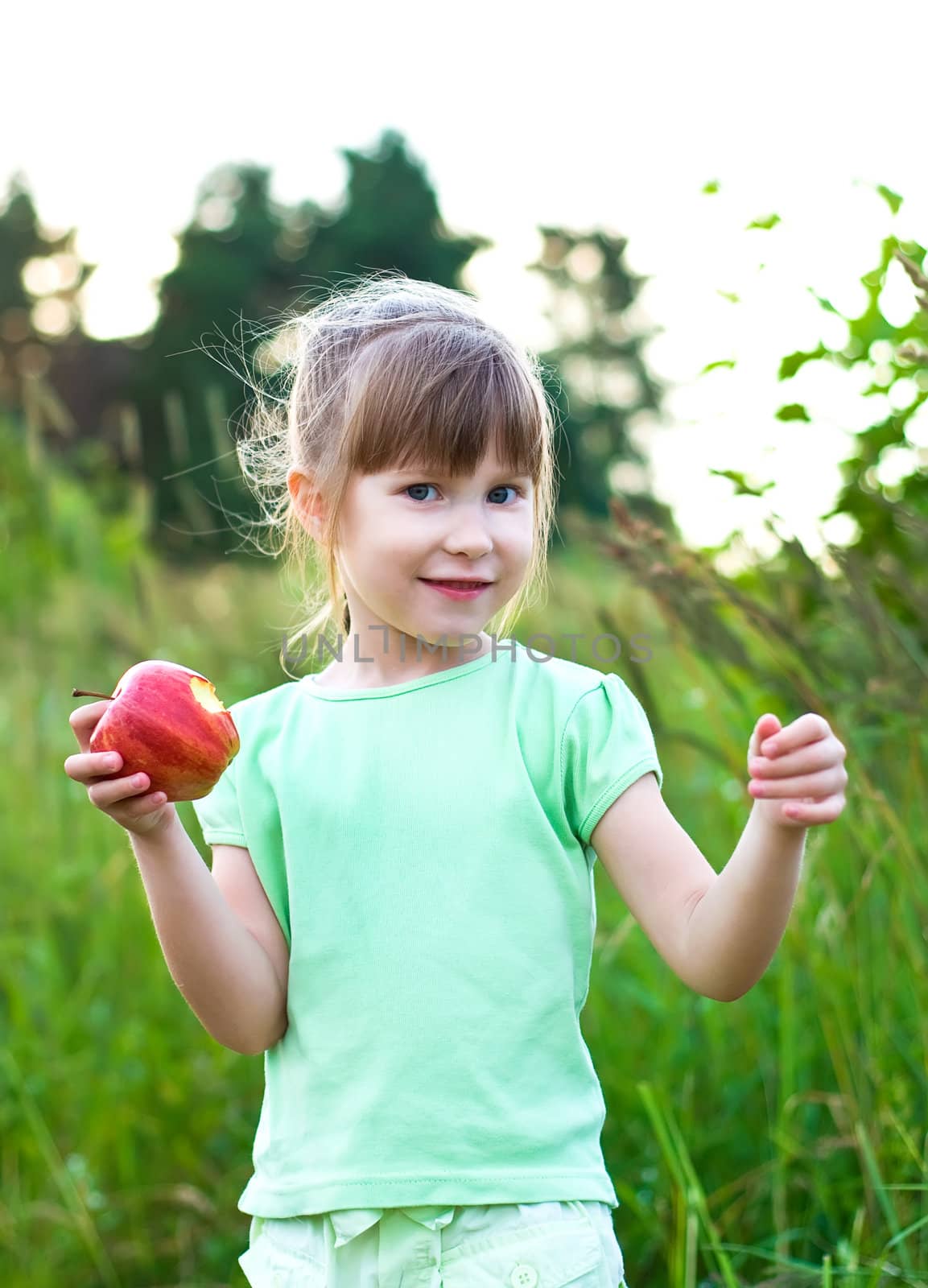 happy smiling girl wih apple in a meadow.