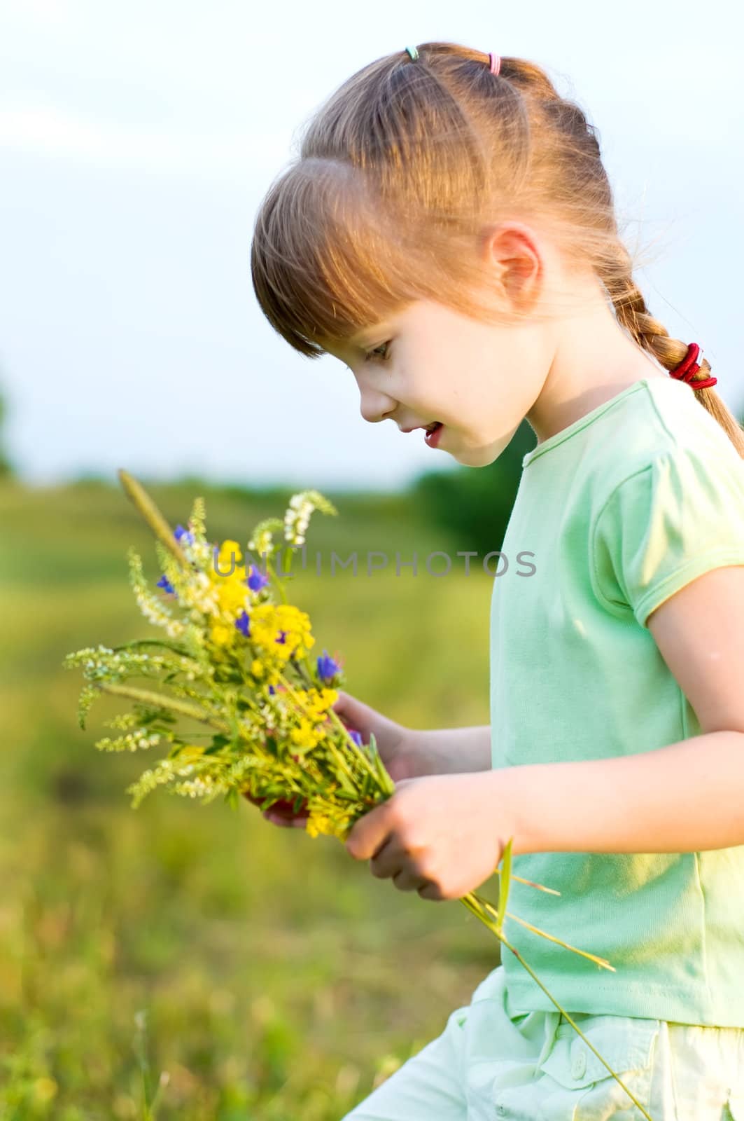 little girl with flowers in a summer meadow.