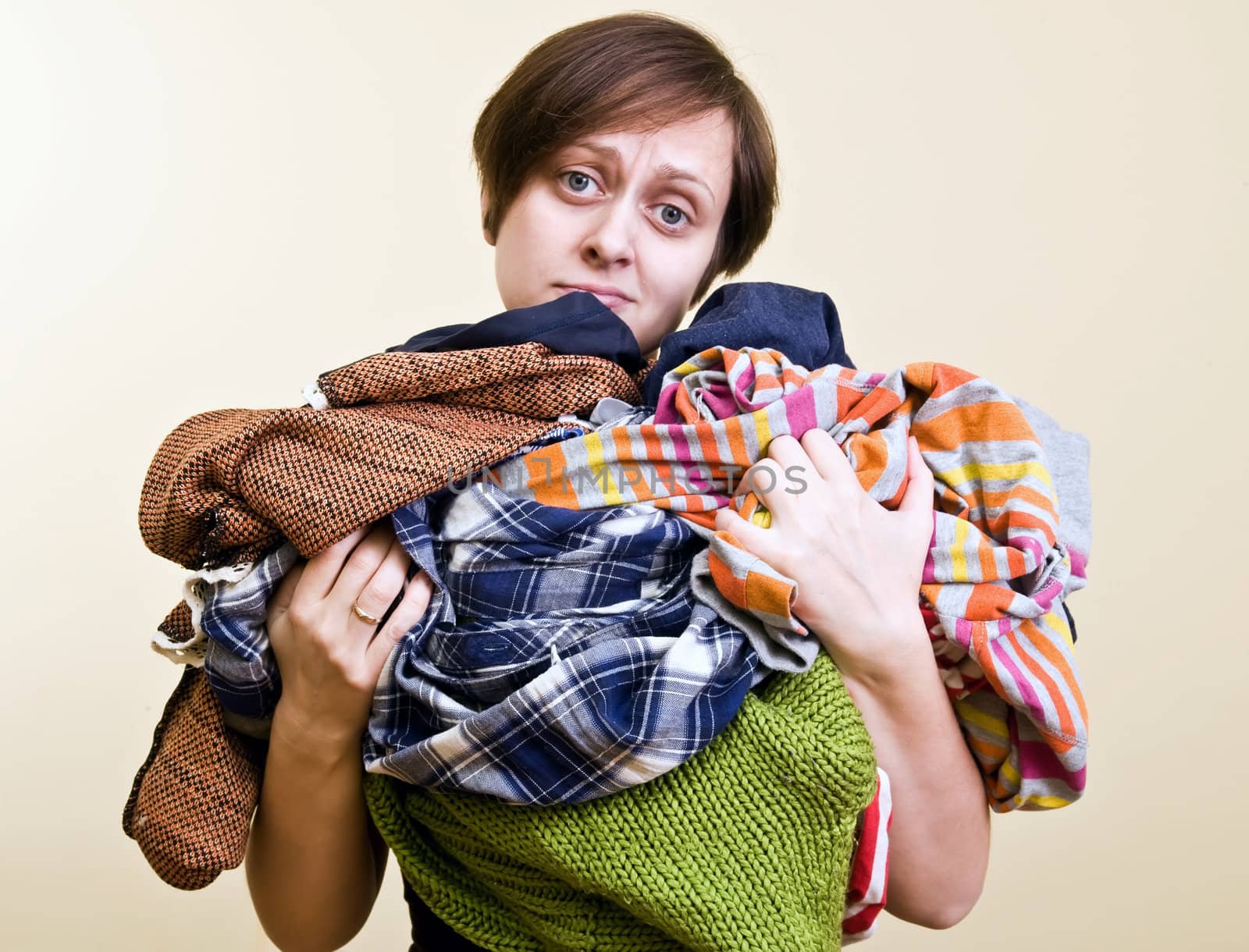 woman holds a lot of loundry in her hands. focus on clothes.