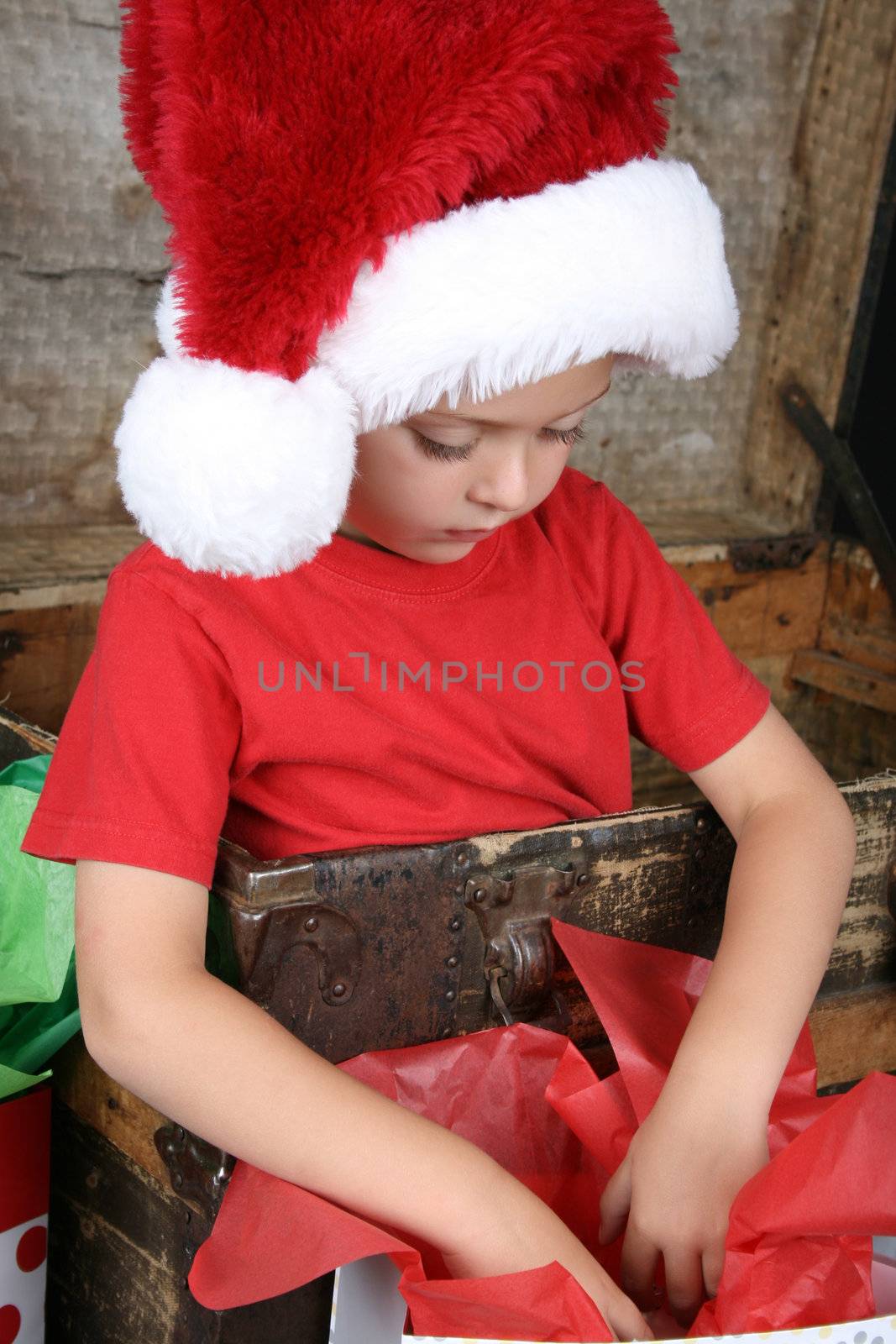 You boy wearing a christmas hat looking in his gift bag