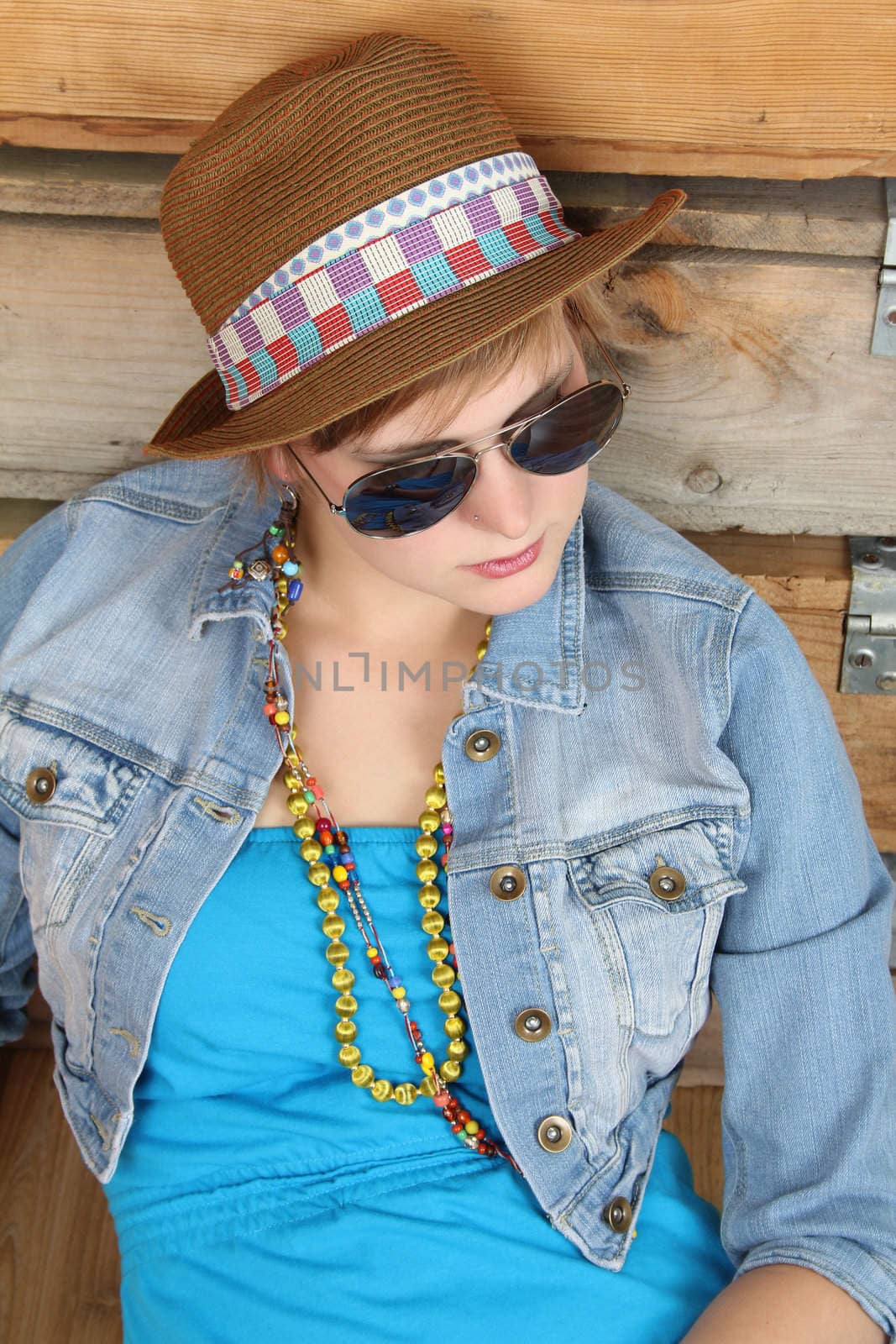 Beautiful young female wearing beach attire sitting against wooden crates