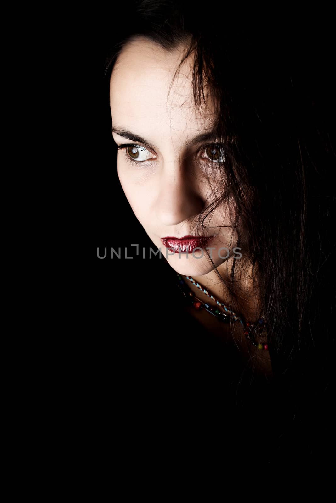 Dramatic brunette female against black background wearing black