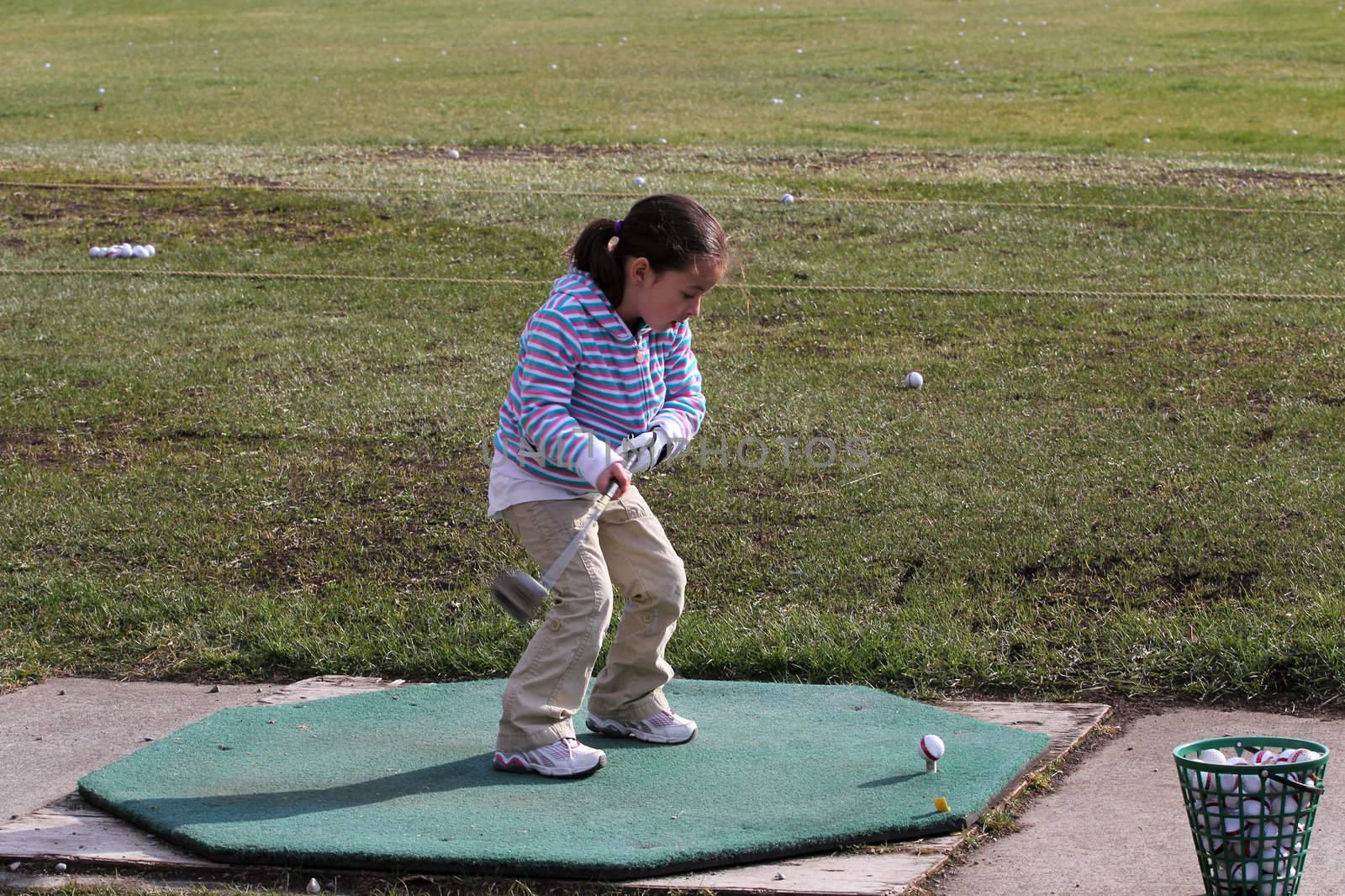 Young female golfer practising on the driving range