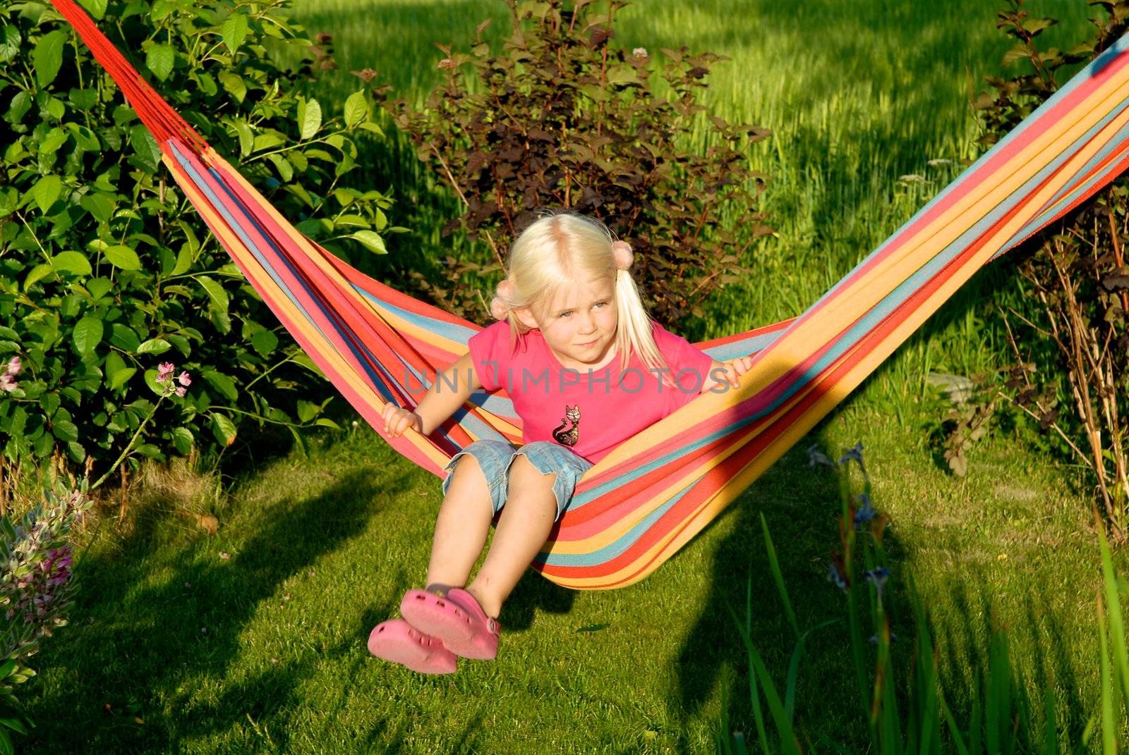 a girl playing on the pink hammock in garden. Please note: No negative use allowed.