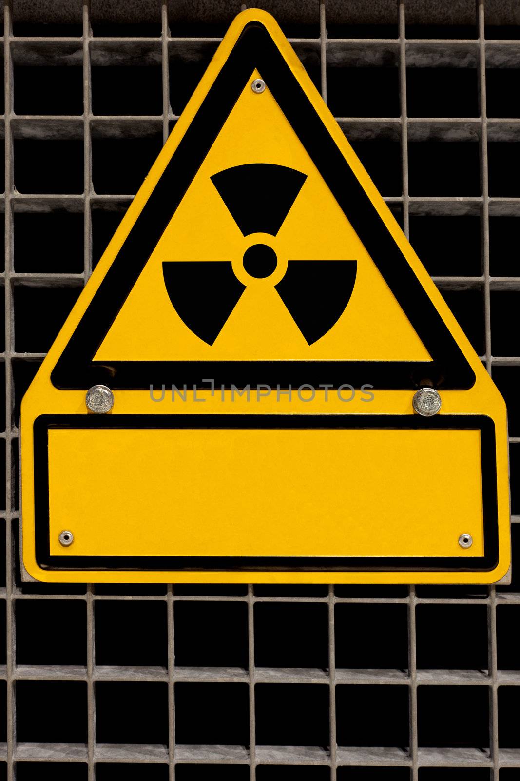 Nuclear radiation sign bolted to steel grid with blank copyspace for your message.