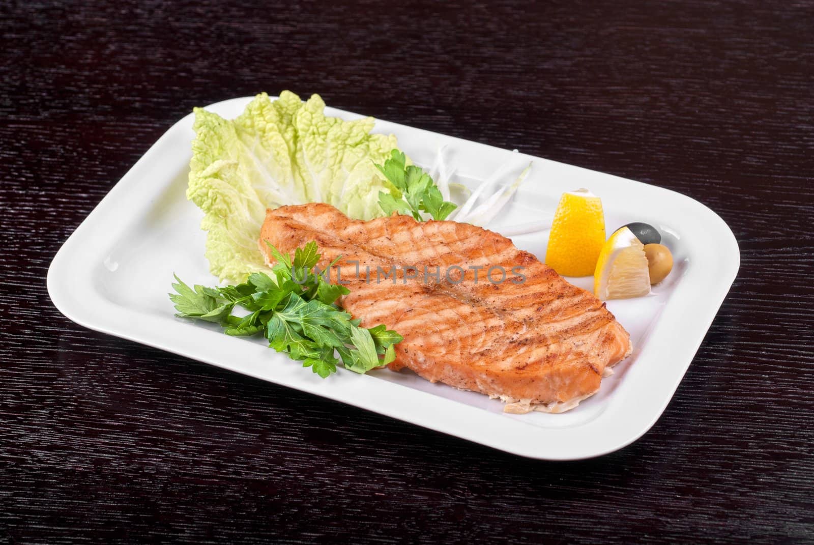Grilled salmon steak with greens,onion, lemon, lime and olive