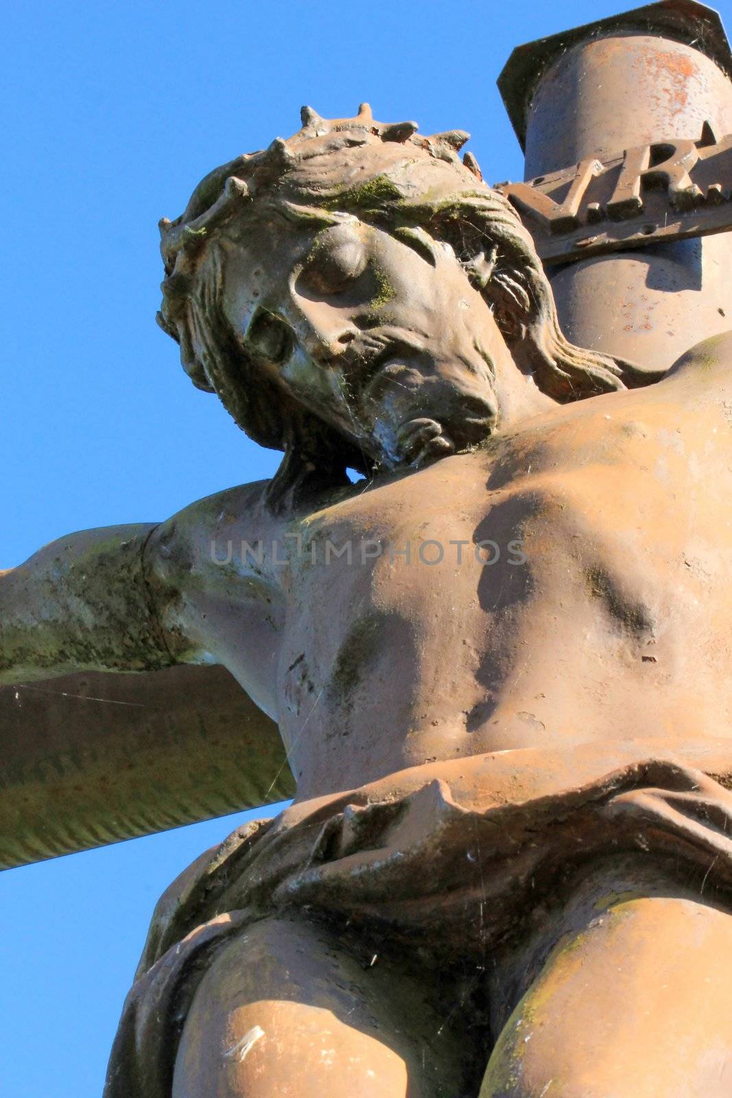Close up of red metallic outdoor statue of Jesus Christ on the cross