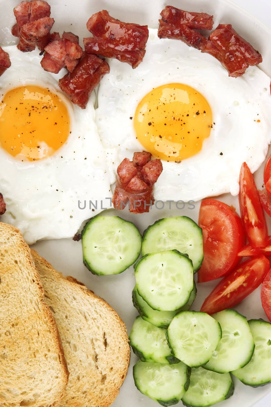 close-up of fried eggs with sausage and vegetables