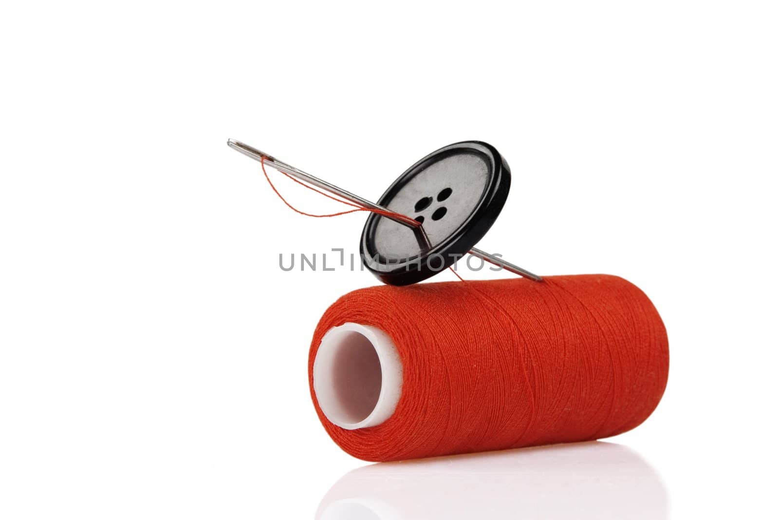 red spool, black button and needle isolated on white background